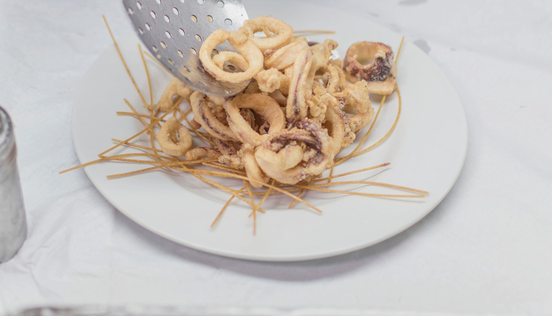 Calamari fritti disposti su un piatto insieme a tagliatelle fritte e sottili.