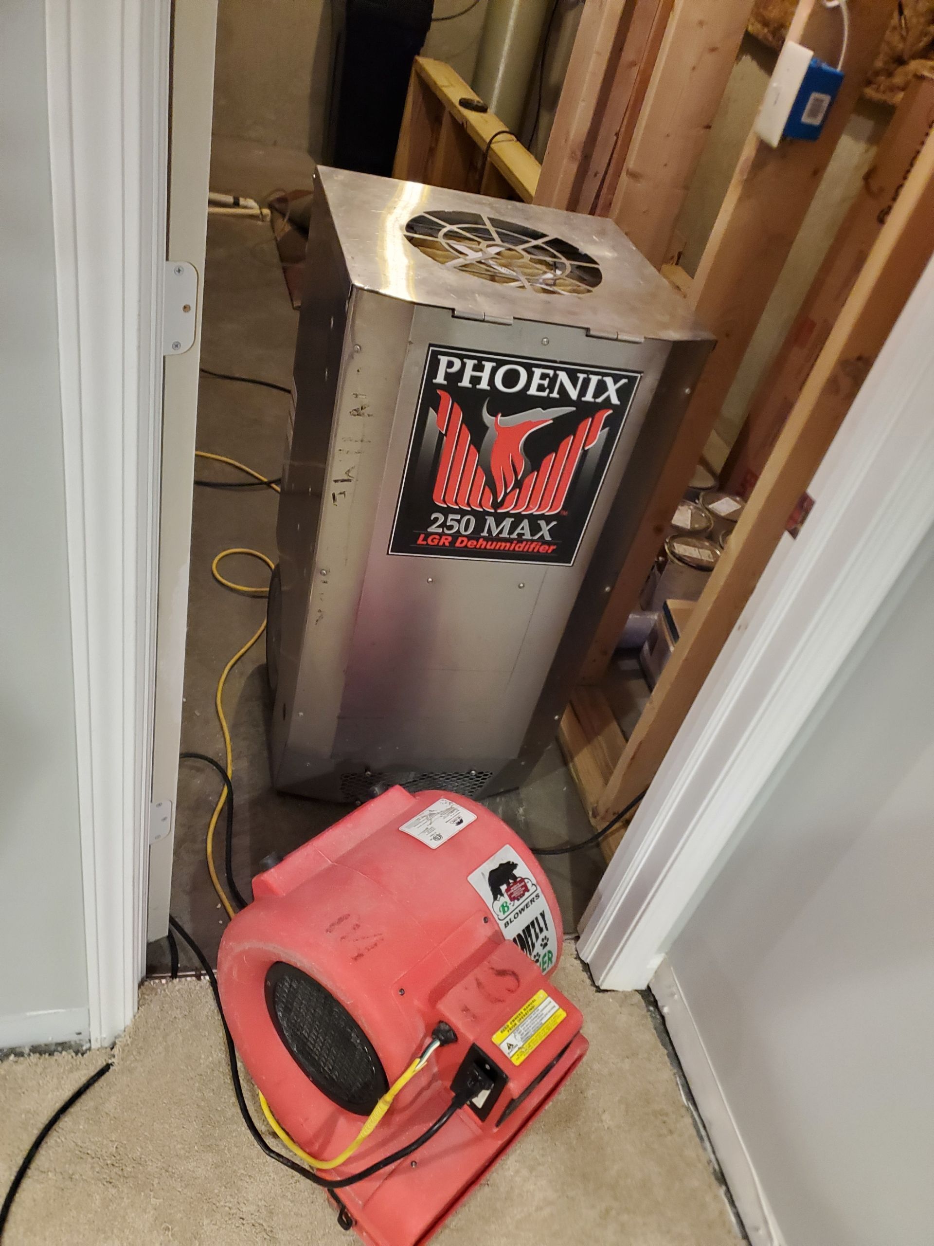 A large dehumidifier and air mover in a hallway during construction.