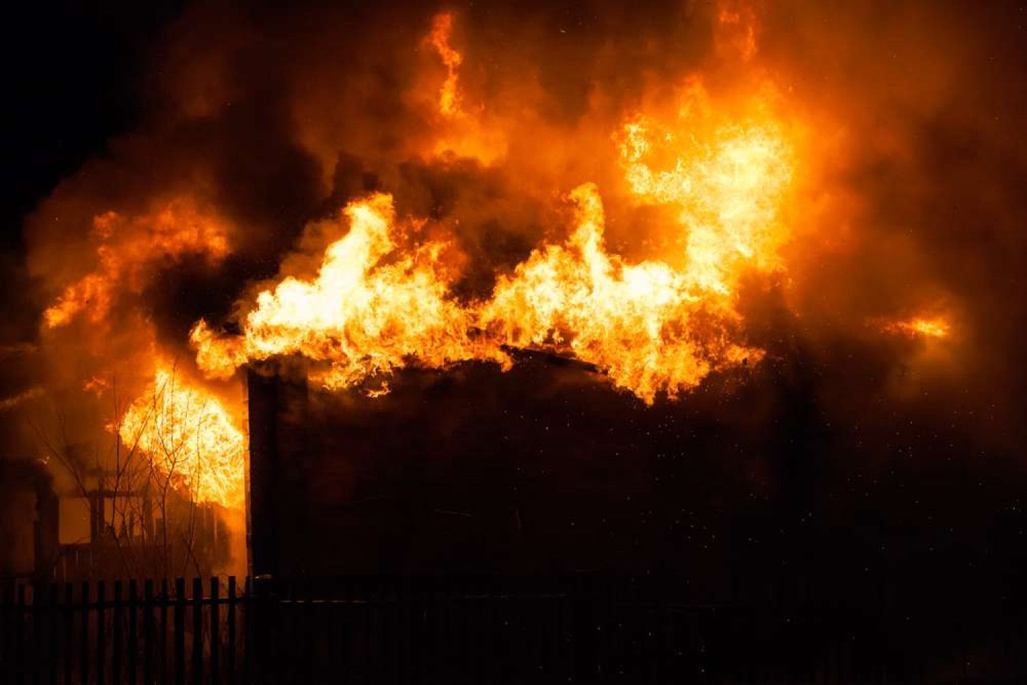 Burning building at night with large orange flames.