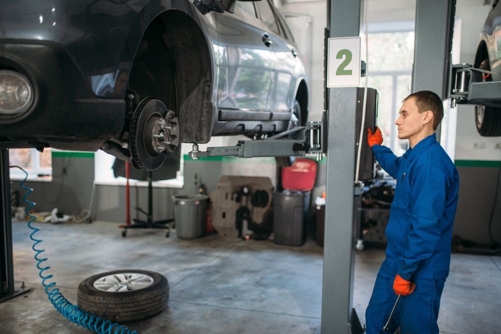 A Mechanic Works on A Car Lifted on A Hoist in A Garage — Grease Monkeys Automotive N Performance in Hervey Bay, QLD