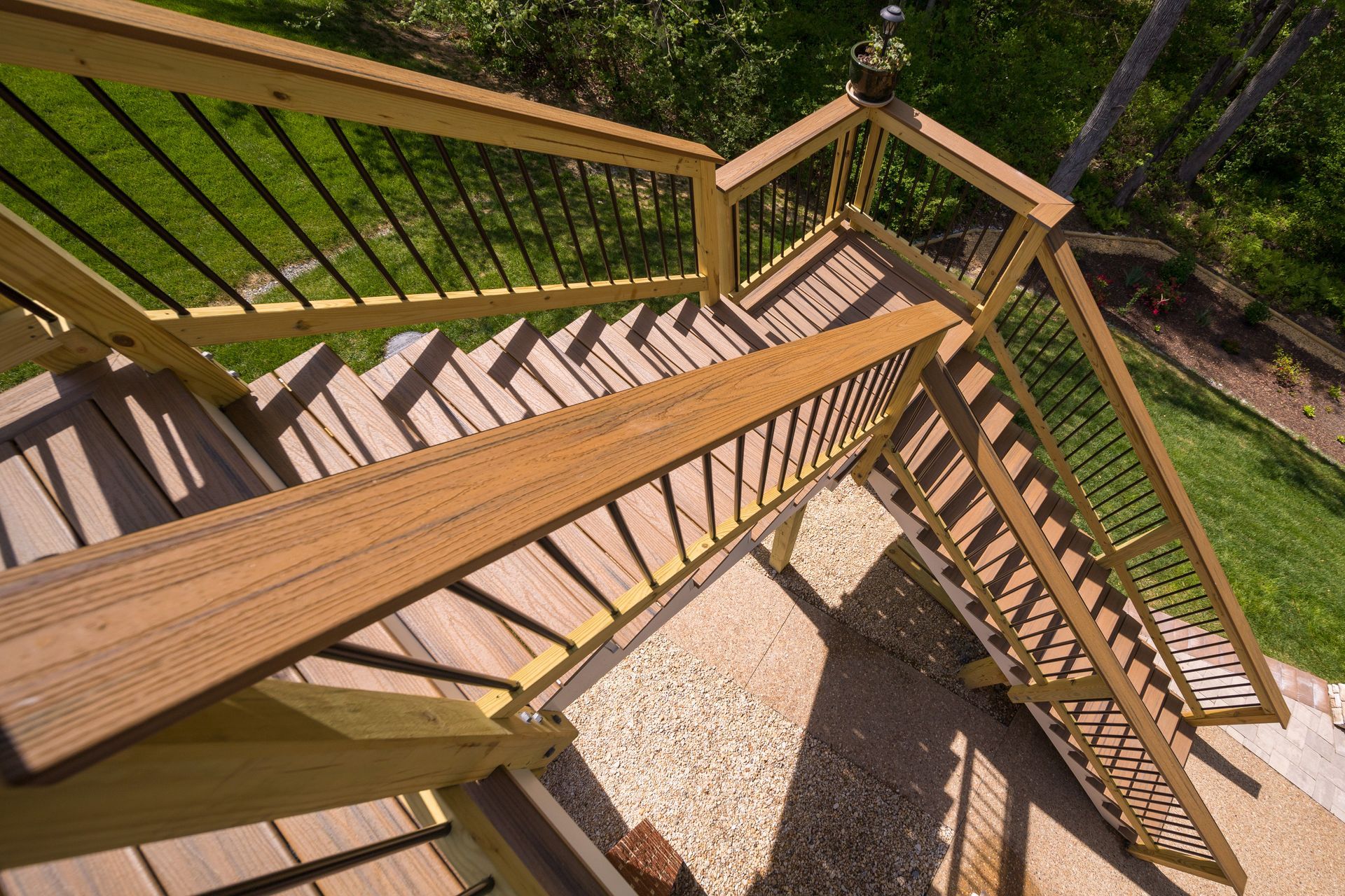 Trex outdoor staircase with railings beside a grassy yard and gravel path, viewed from above.