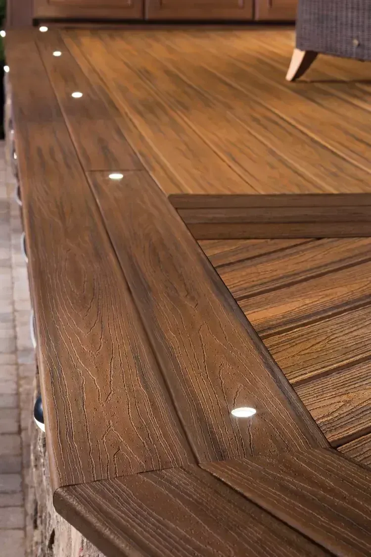 A close-up view of a wooden deck edge with recessed LED lights installed along the perimeter.