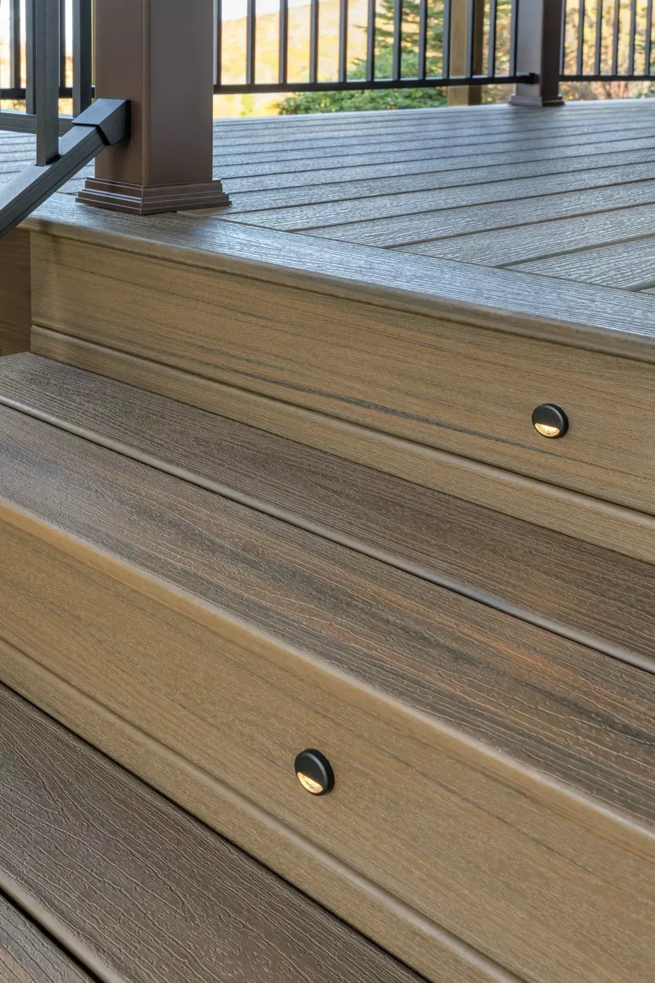 Brown composite deck stairs with built-in circular step lights on each riser.