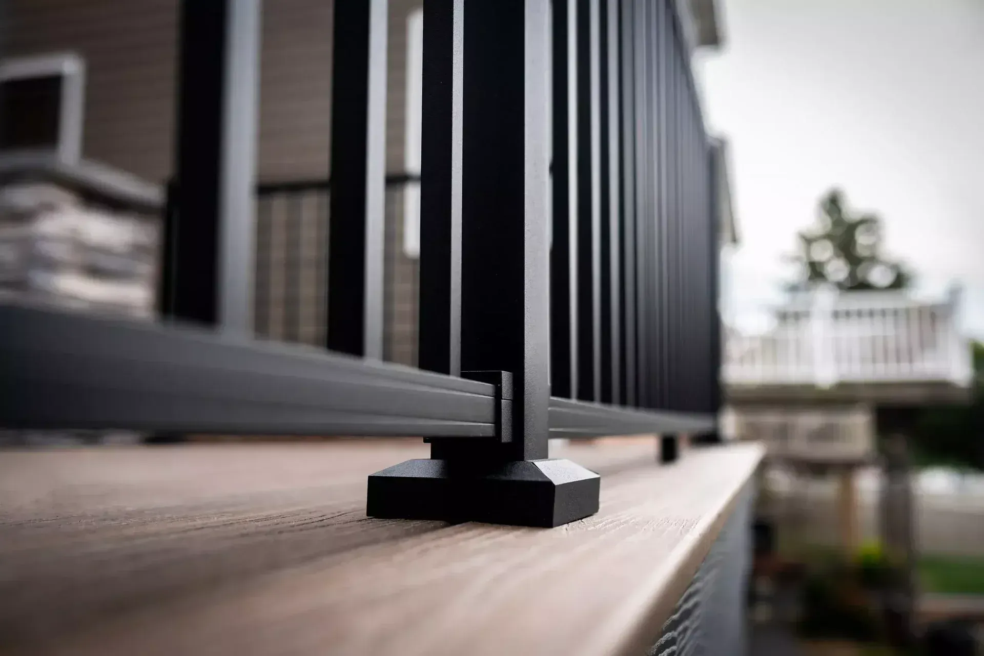 A close-up of a black metal deck railing with vertical balusters mounted on a brown composite deck surface.