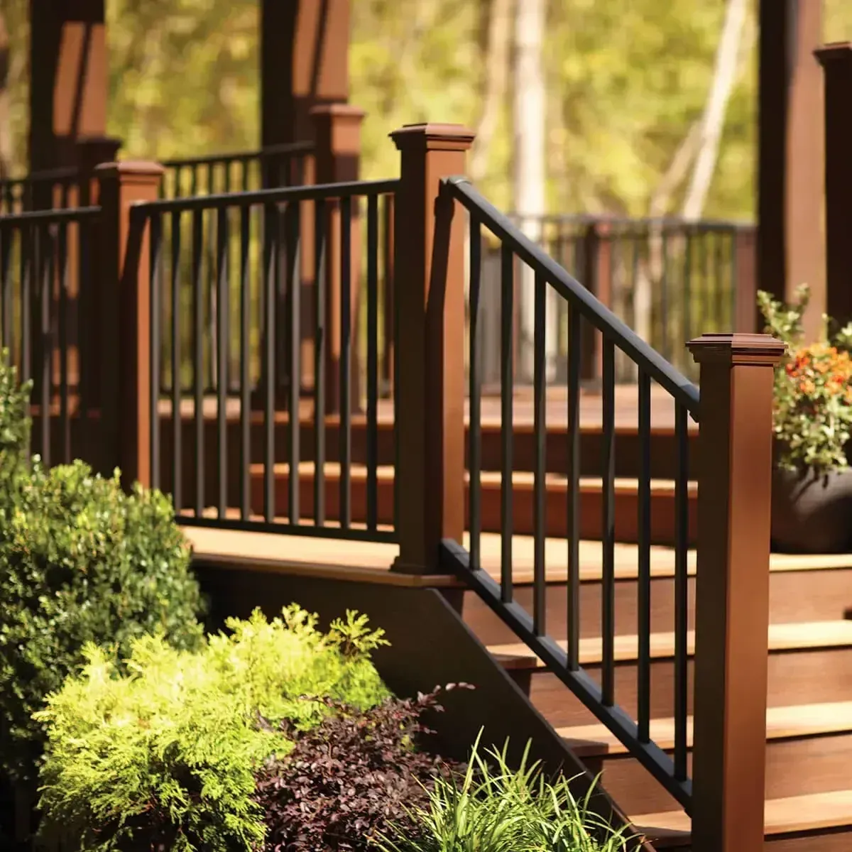 A wooden deck with white railings and stairs leading to a brick house exterior with a screened porch.