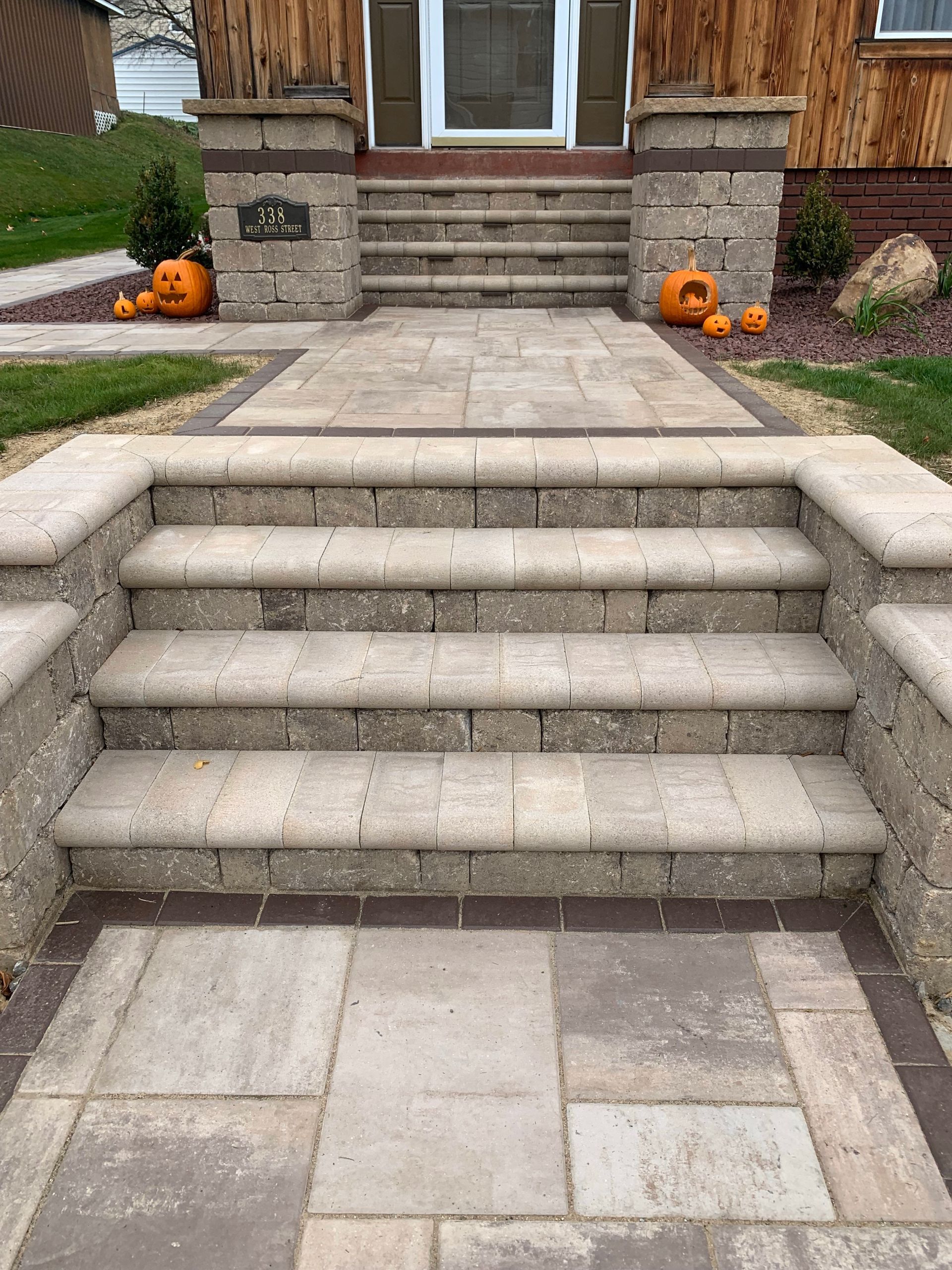 Front steps leading to a house entrance, with stone walkway and small Halloween pumpkin decorations.