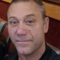 Man with short, graying hair looking directly at the viewer with a slight smile.