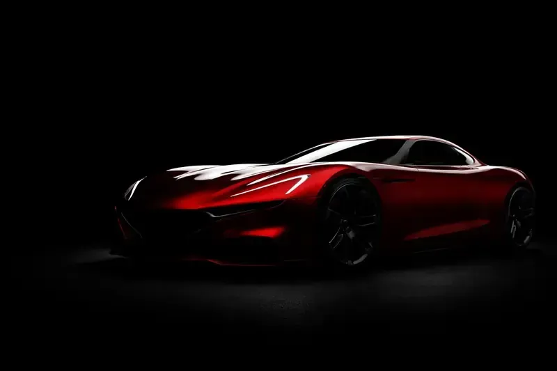 Red sports car, lit dramatically against a black background.