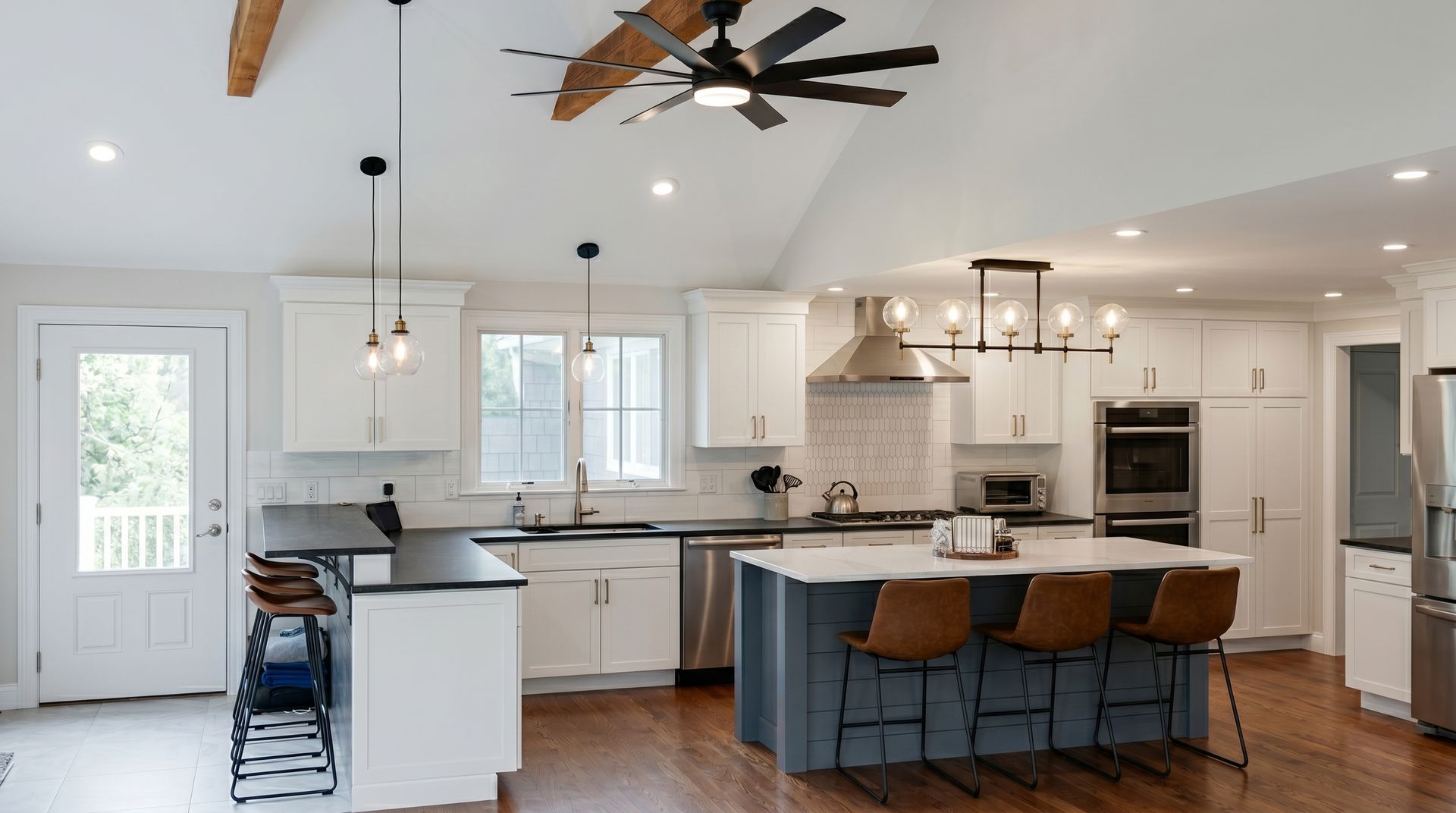 Bright modern kitchen with white cabinets, wood floors, island seating, and stainless appliances