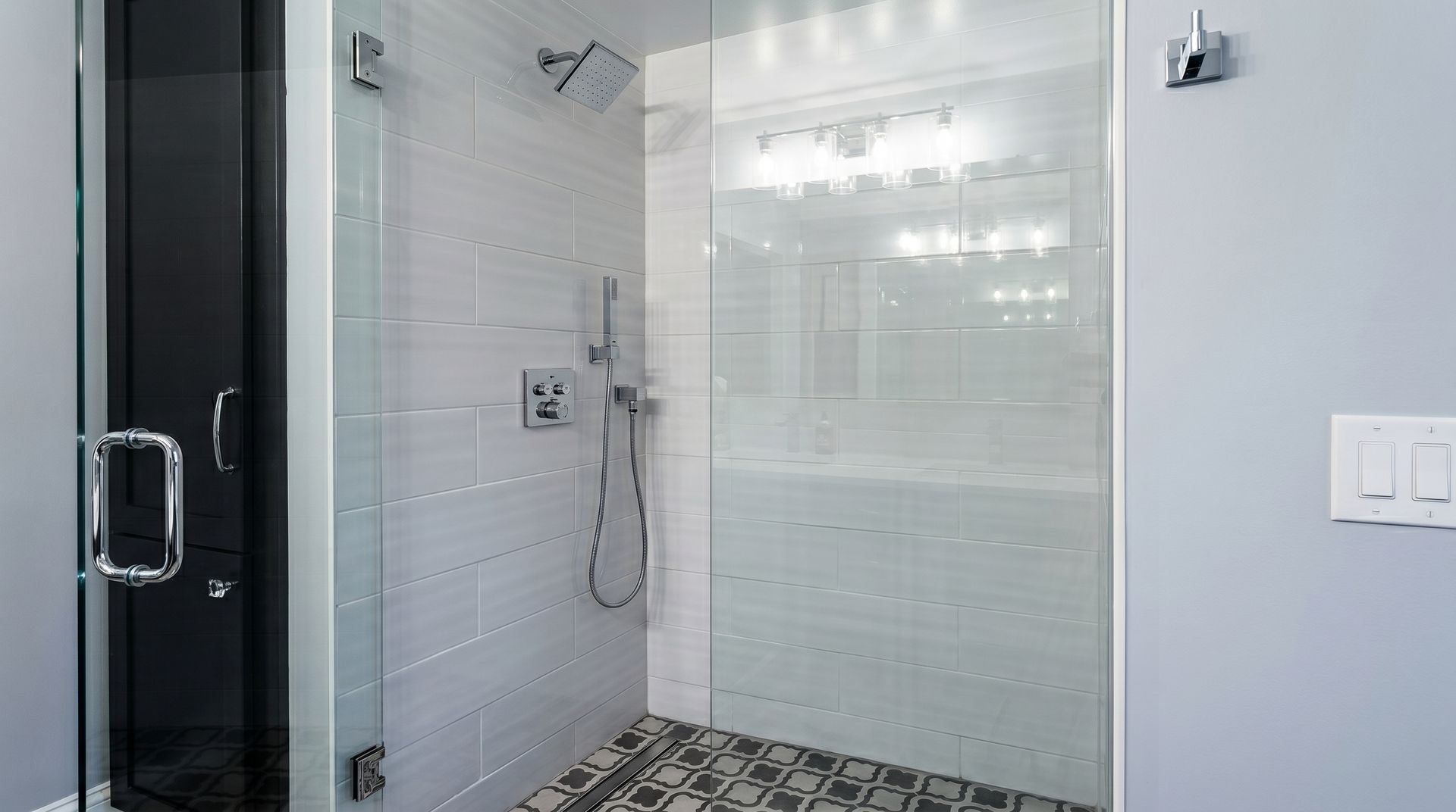 Glass shower with tiled walls and a handheld showerhead in a modern bathroom
