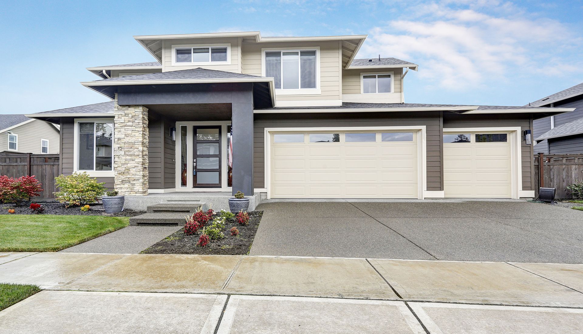 A large house with two garage doors and a concrete driveway