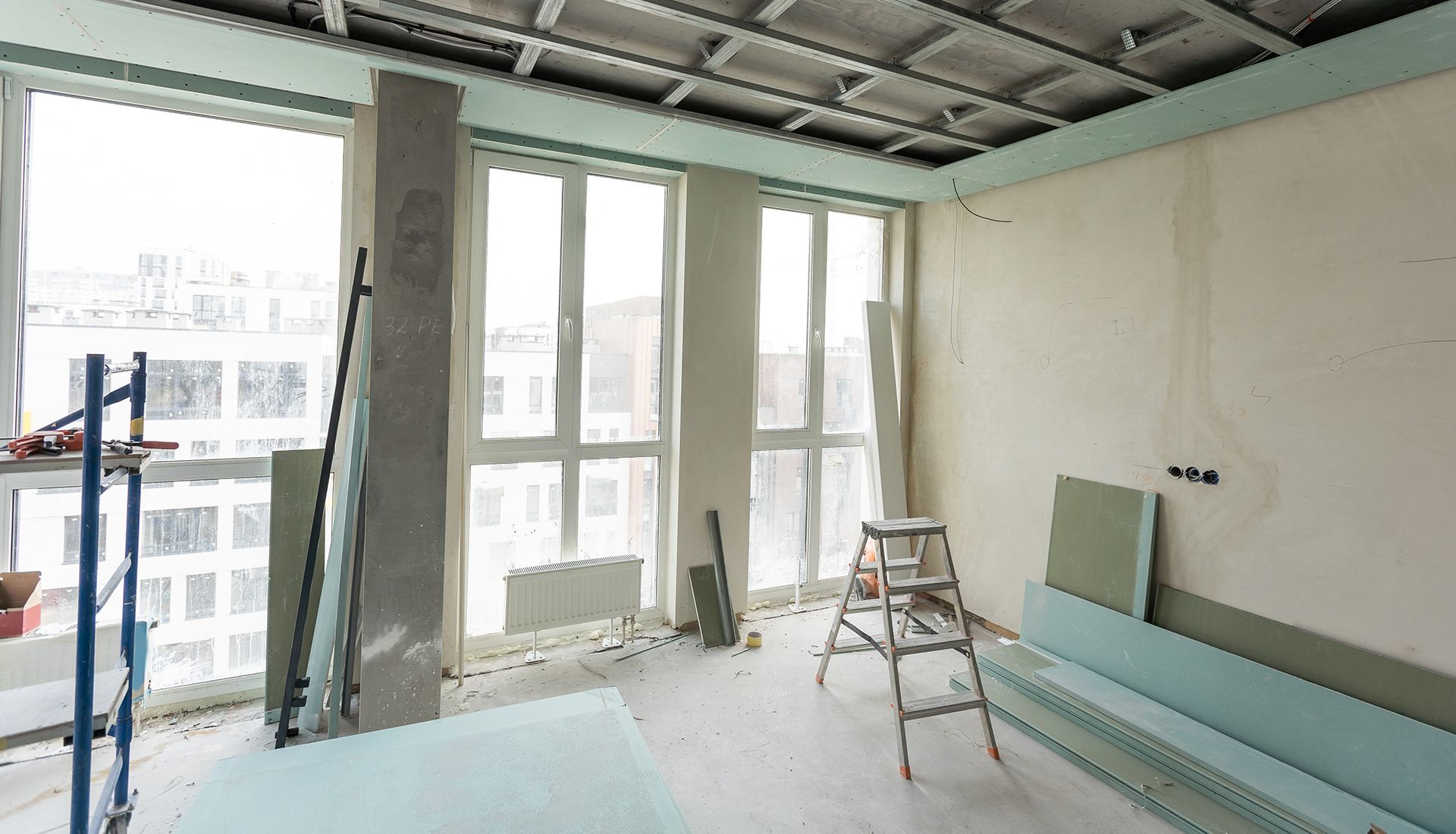 A room under construction with a lot of windows and a ladder.