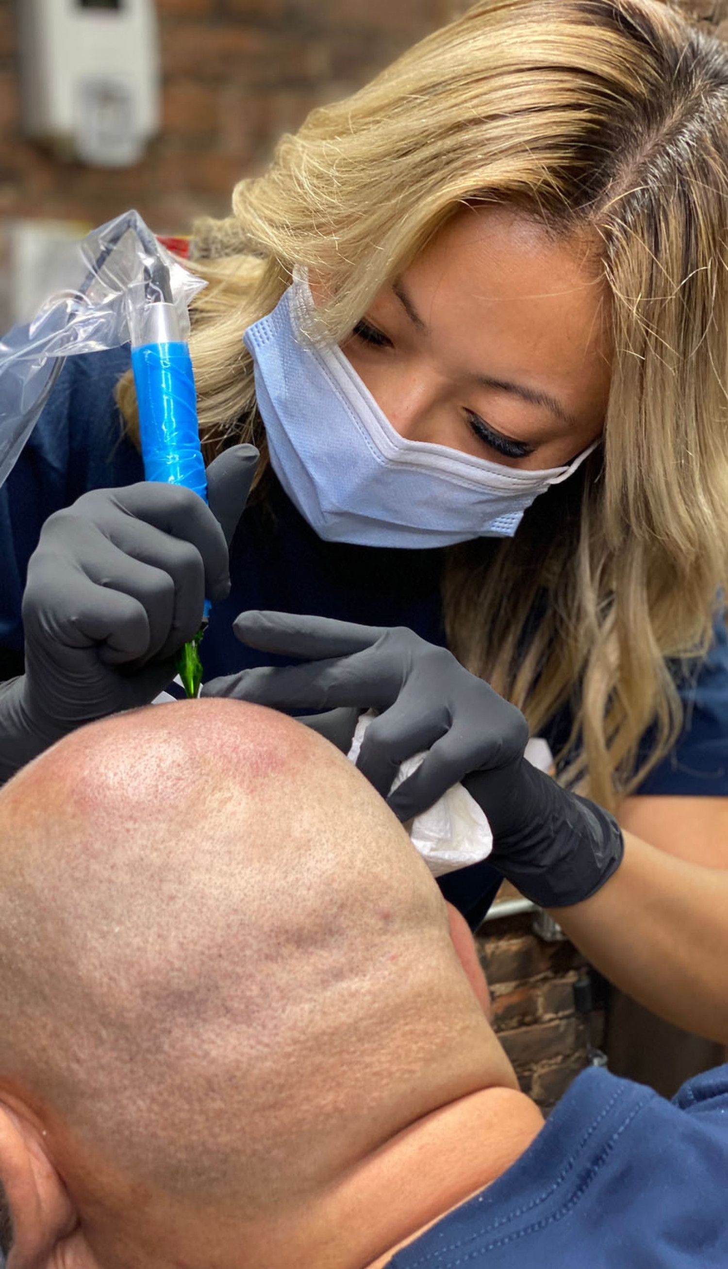 Masked dentist using a blue dental tool to treat a patient in a chair