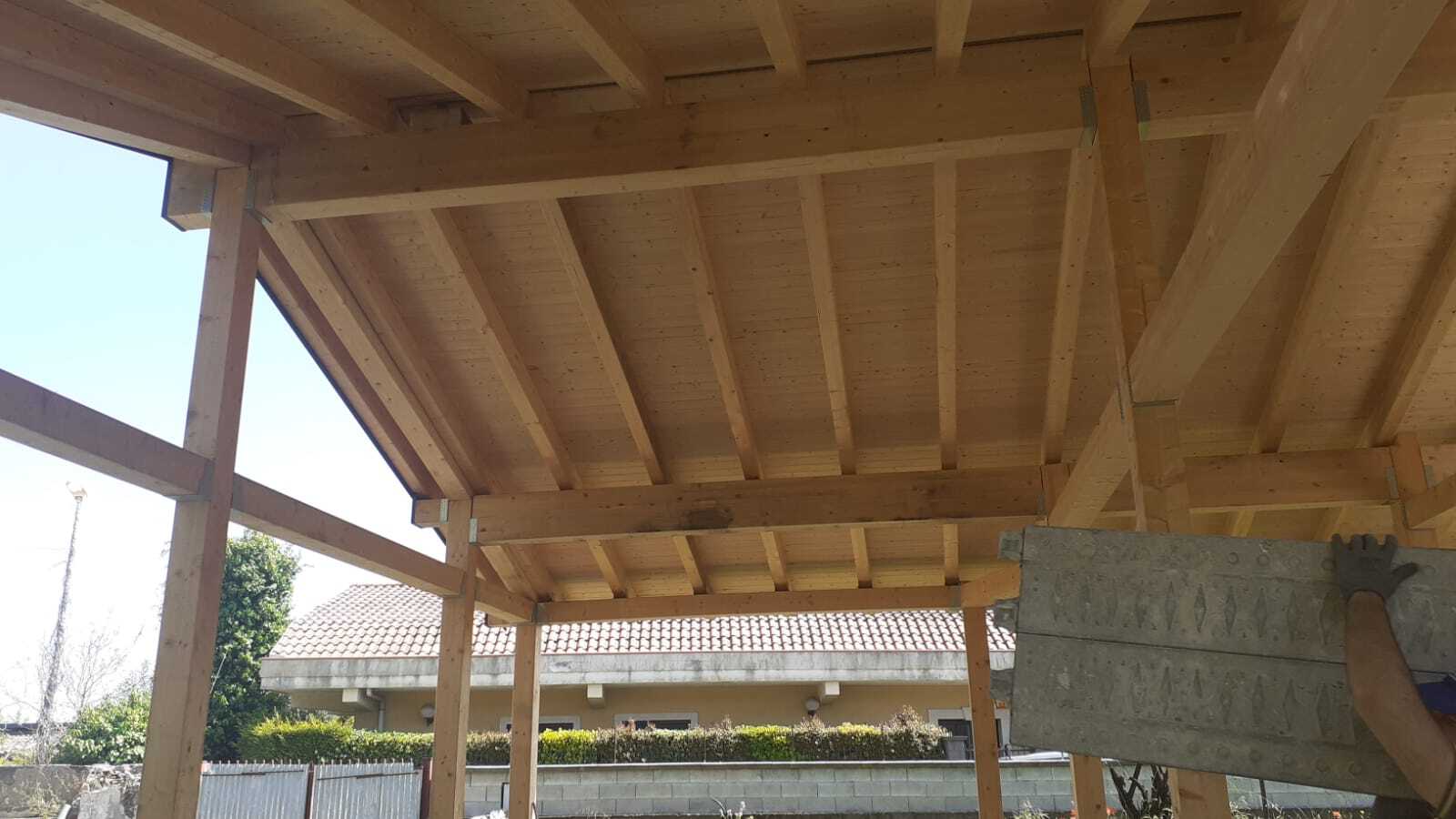 Struttura in legno con pannelli a vista. Una persona tiene in mano un pannello isolante grigio.