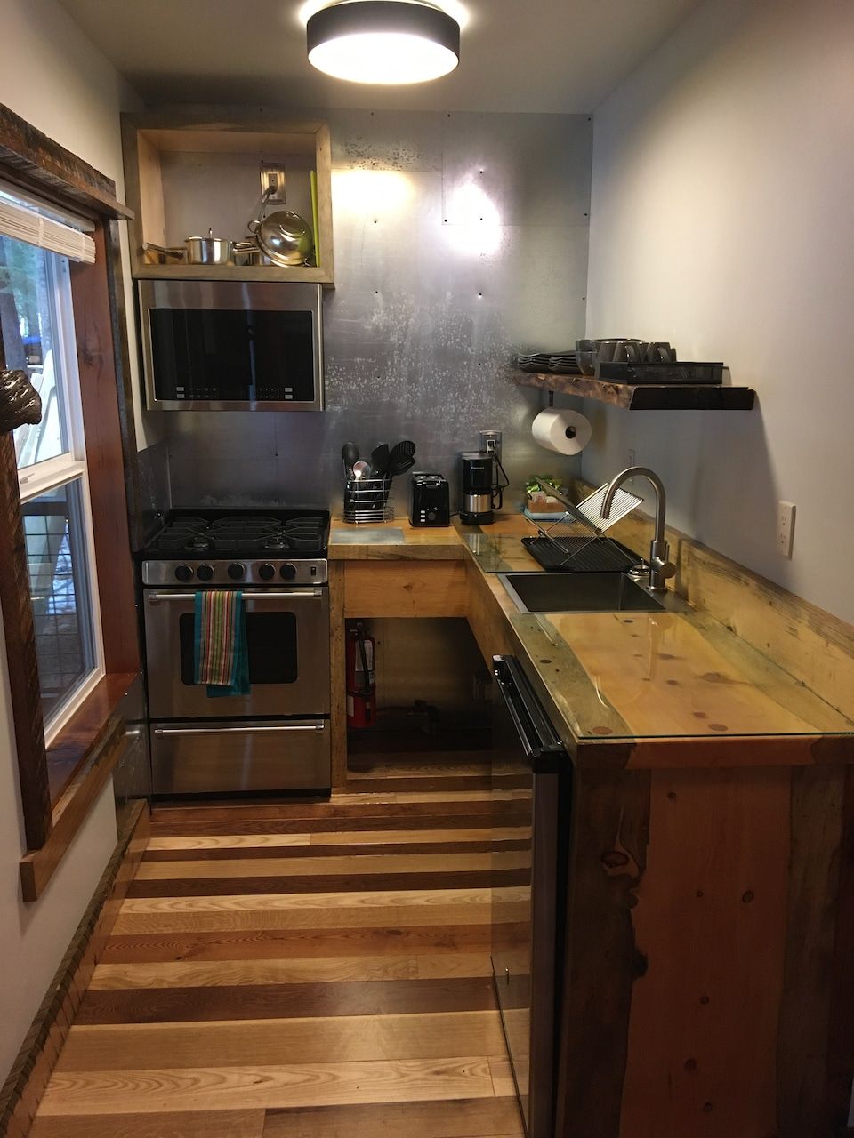 A kitchen with a stove , sink , and a window.