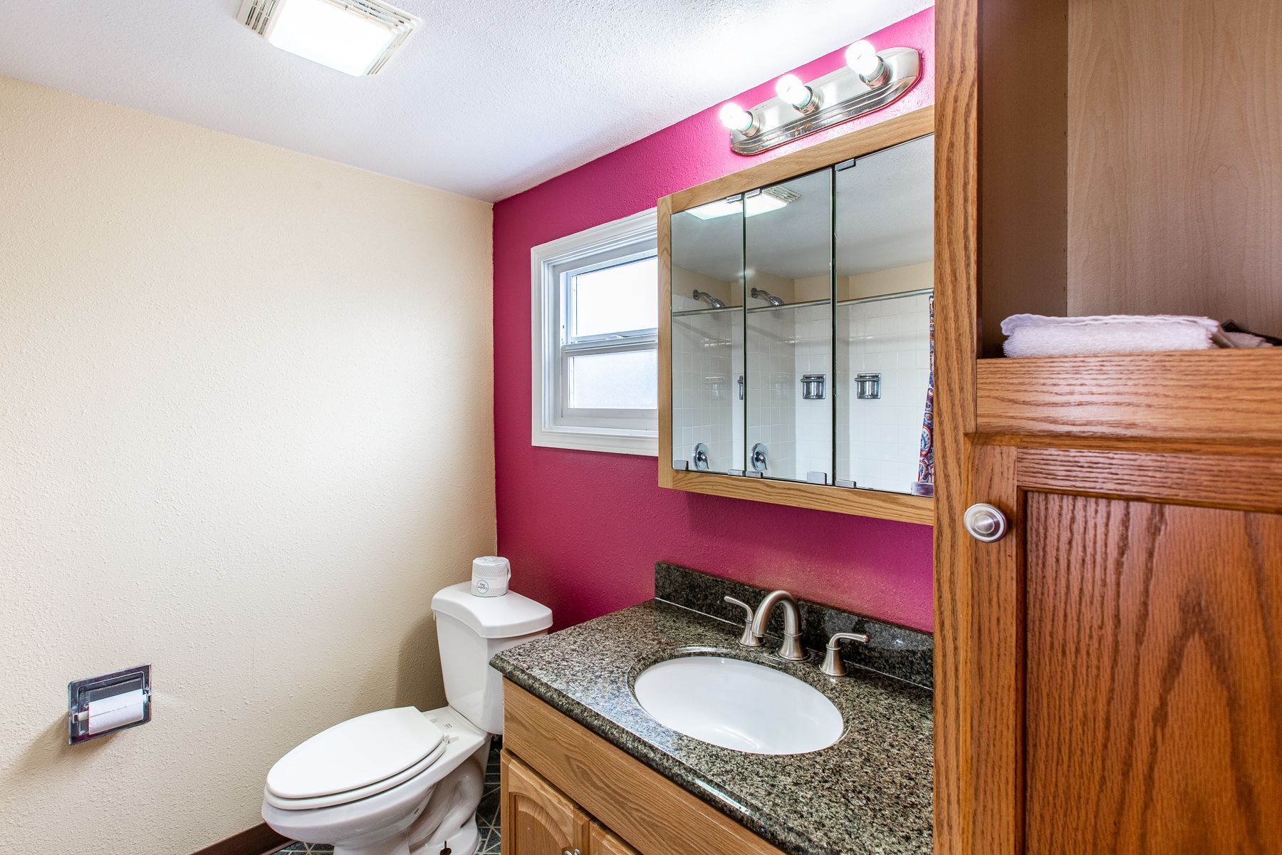 A bathroom with a toilet , sink and mirror.