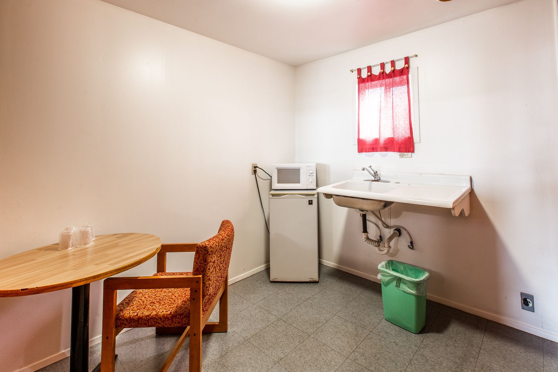 A room with a table , chairs , sink and microwave.