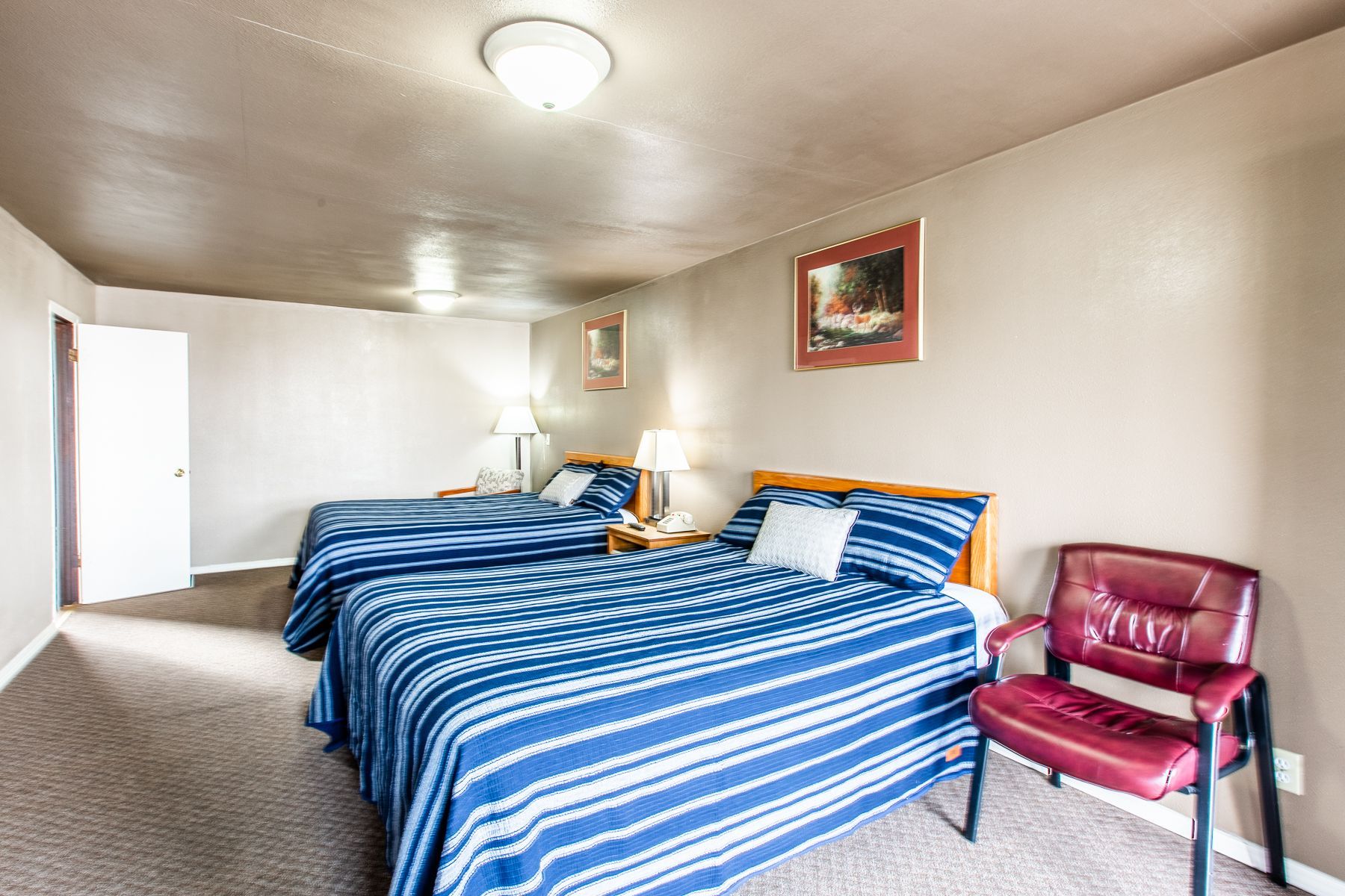 A hotel room with two beds and a chair.