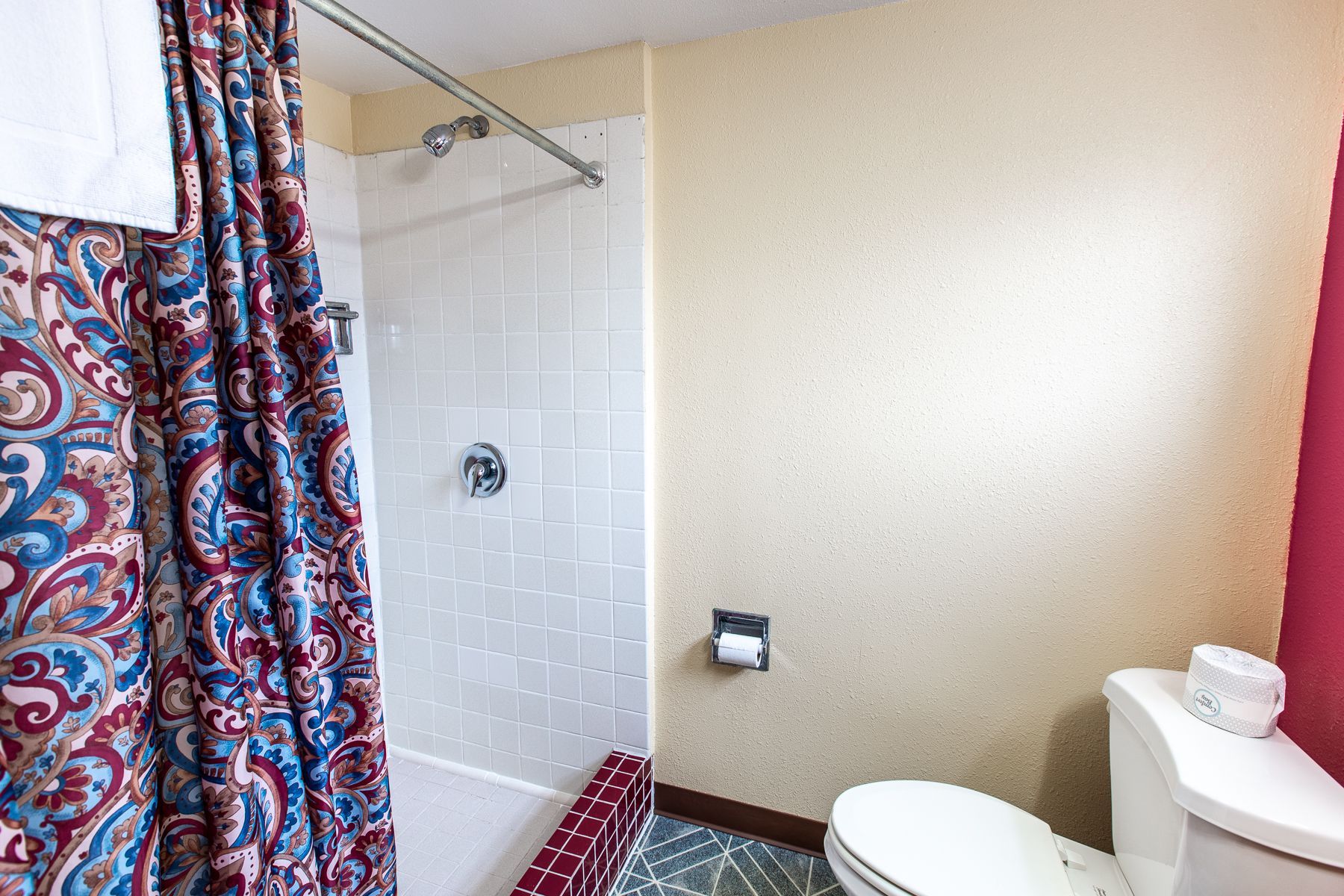 A bathroom with a toilet , shower and bathtub.