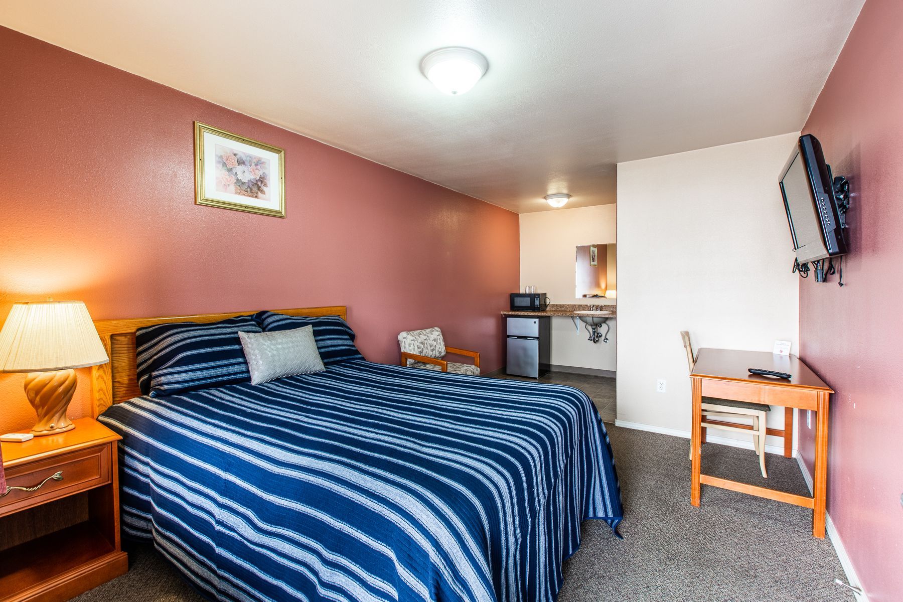 A hotel room with a king size bed and a flat screen tv.