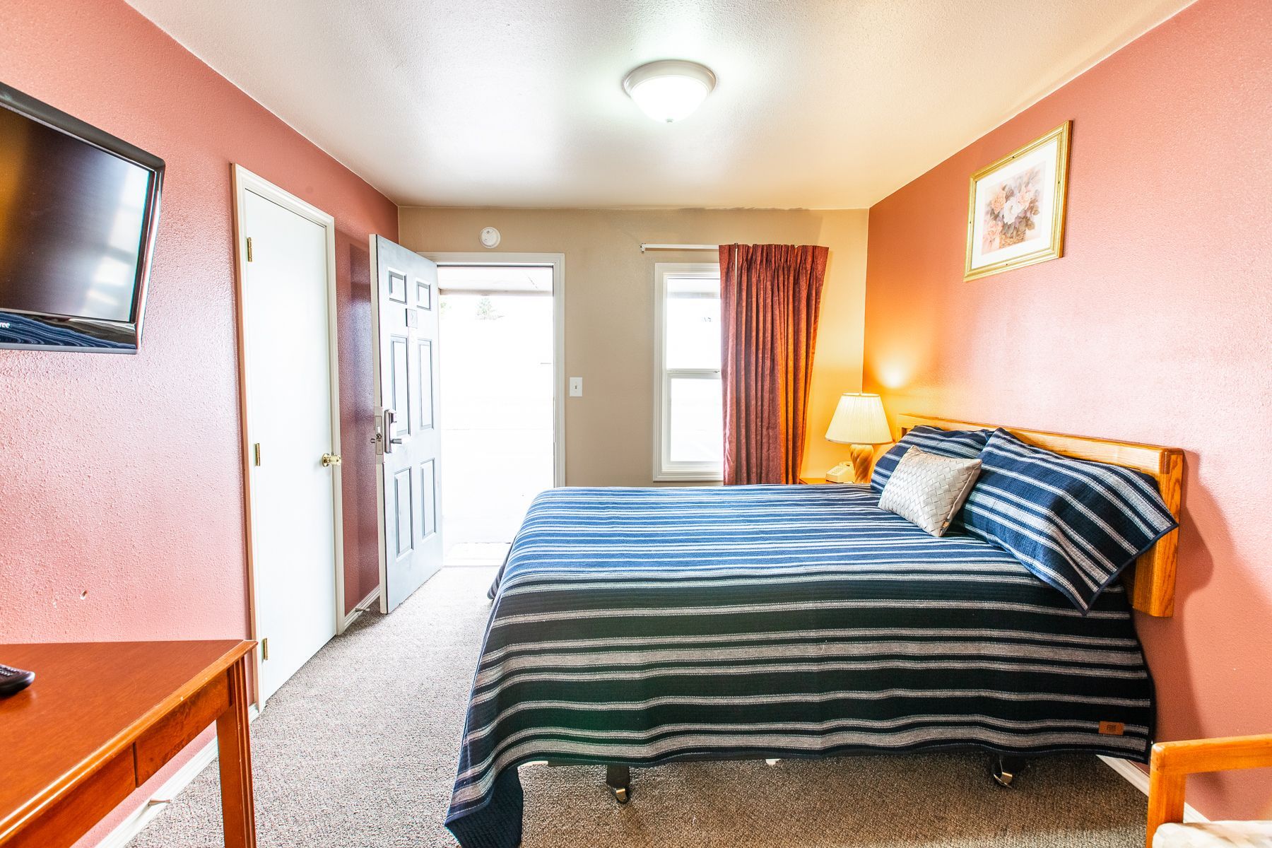 A hotel room with a king size bed and a flat screen tv.