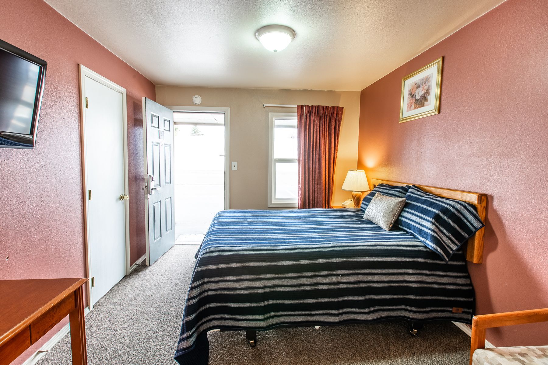 A hotel room with a king size bed and a flat screen tv.