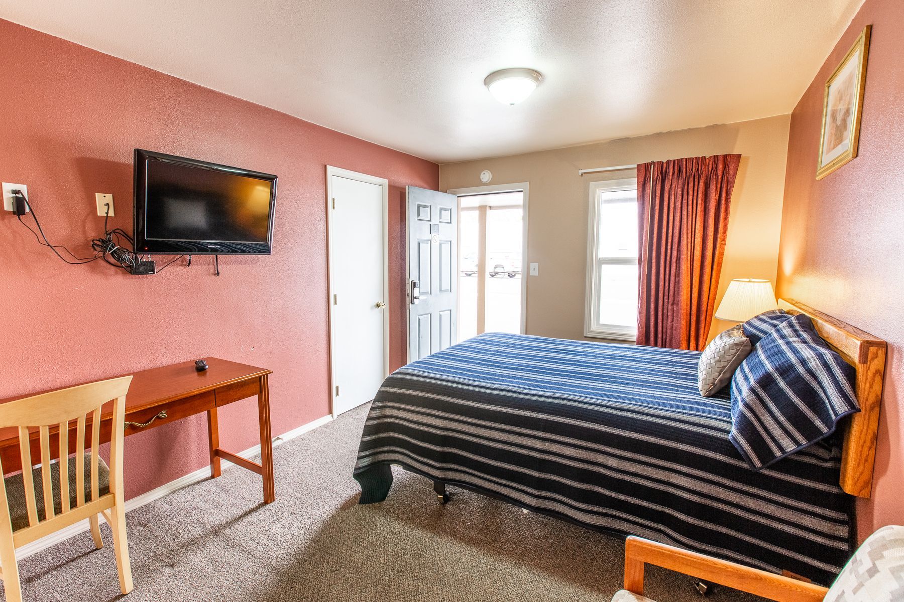 A hotel room with a bed , desk , chair and television.