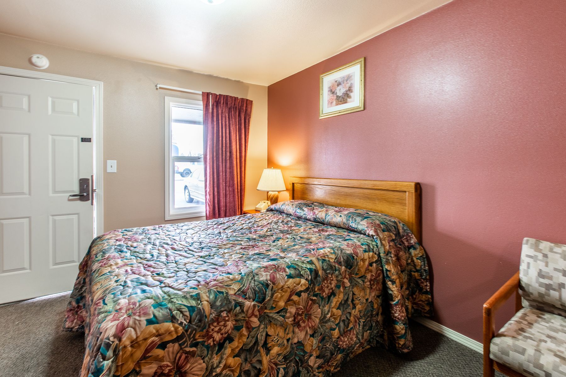A hotel room with a king size bed and a chair.