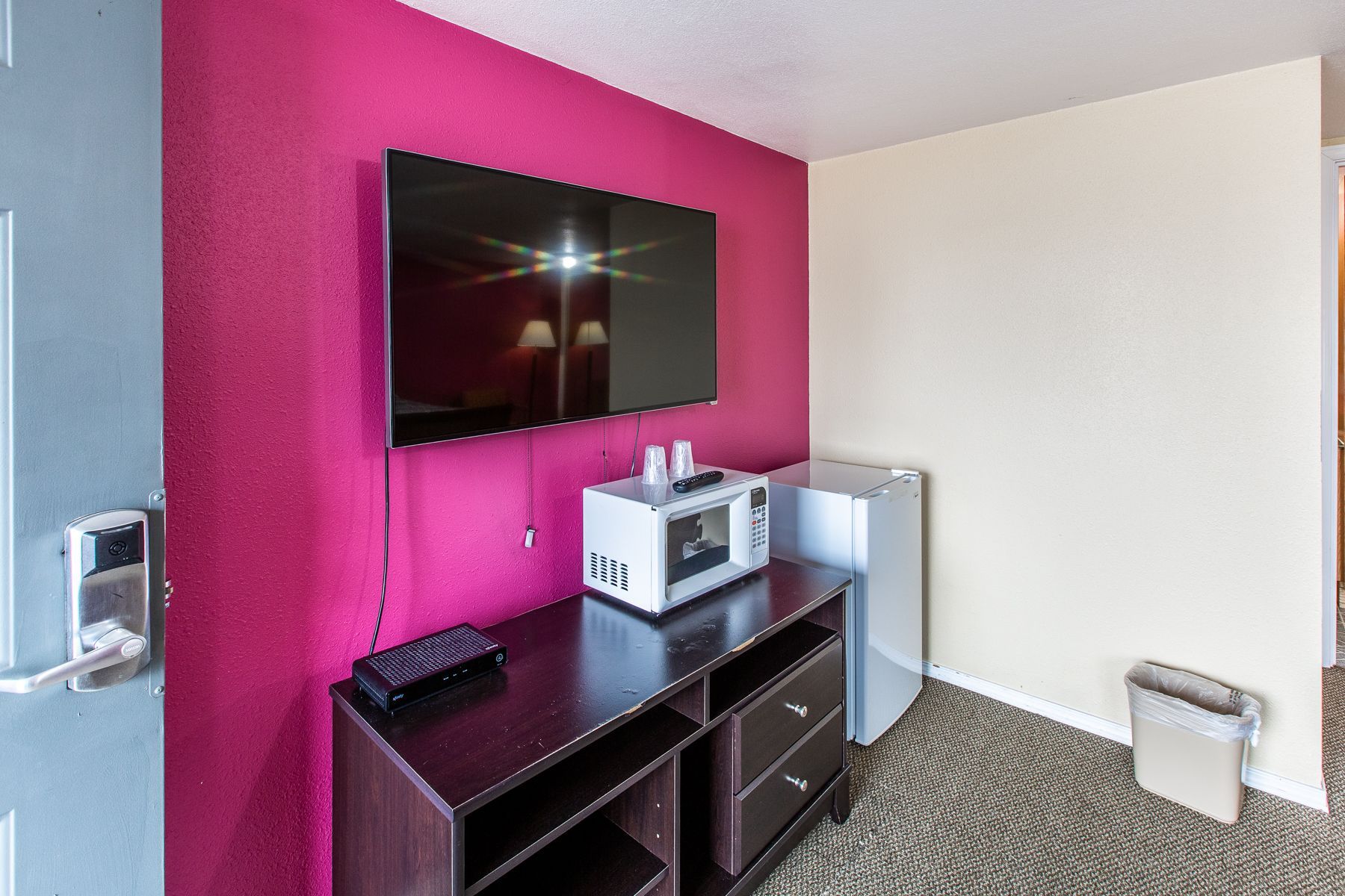 A hotel room with a flat screen tv , microwave and refrigerator.