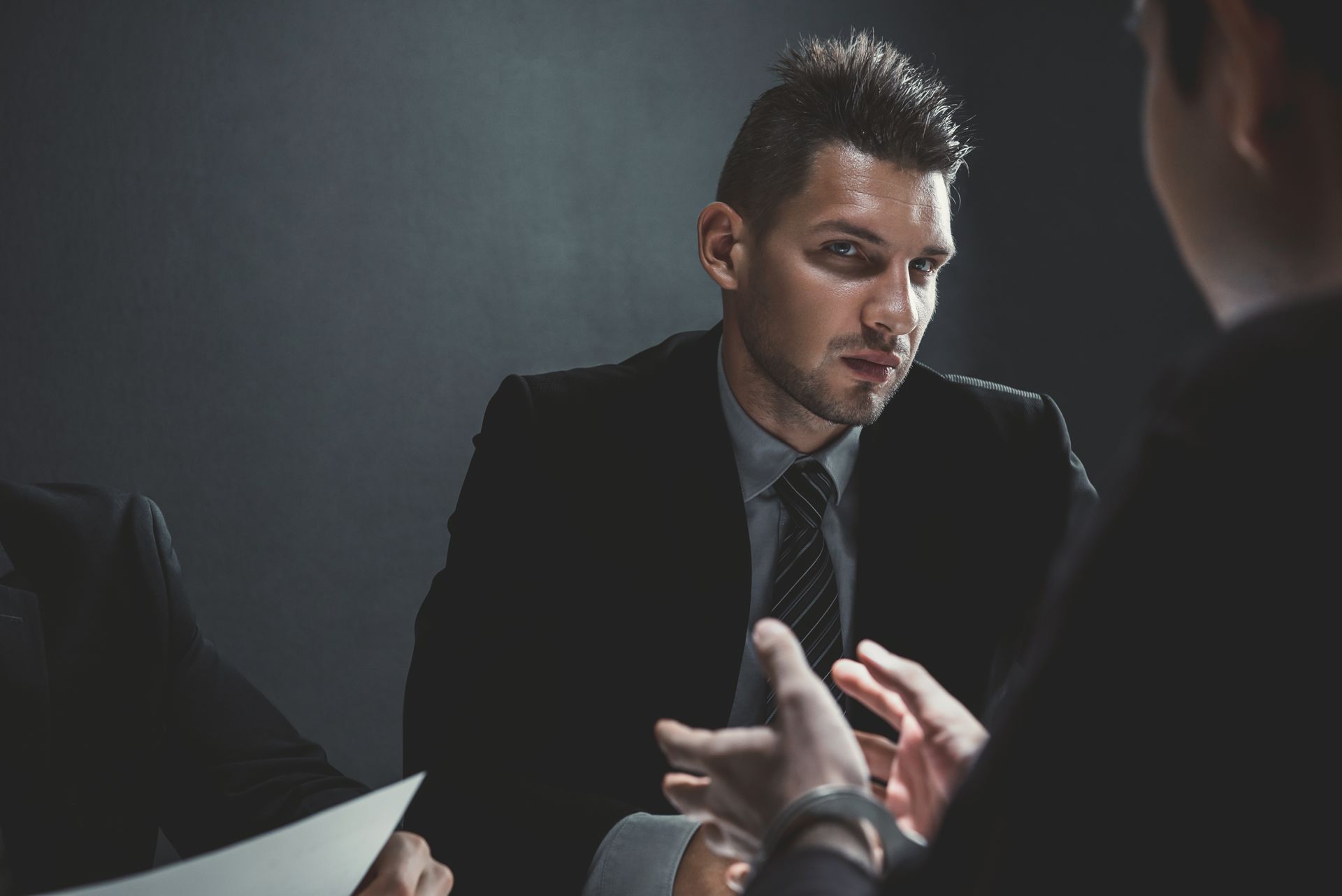 Man in a dark suit and tie listening intently to the criminal lawyer during a serious consultation. Man in a dark suit and tie listening intently to the criminal lawyer during a serious consultation.