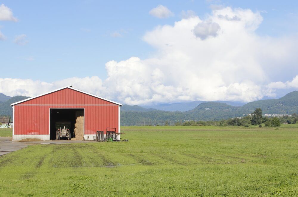 A red barn is sitting in the middle of a grassy field — Connect Mid Coast Electrical Services In Taree, NSW