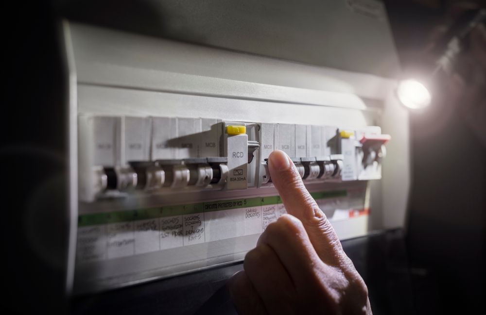 A Man Is Writing In A Notebook In Front Of An Electrical Box — Connect Mid Coast Electrical Services In Taree, NSW