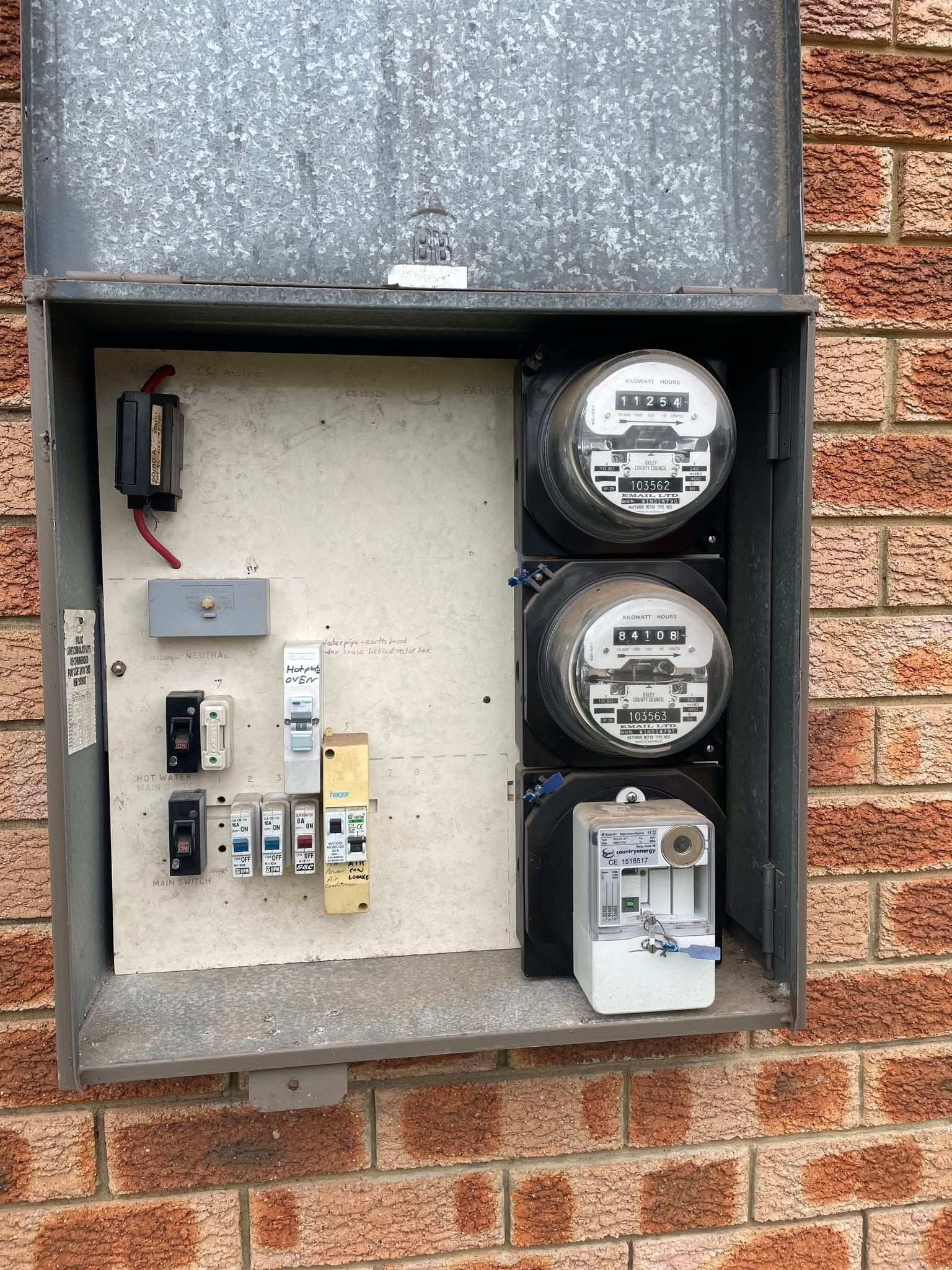 Open electrical meter panel on a brick wall with two utility meters and circuit breakers inside — Connect Mid Coast Electrical Services In Taree, NSW