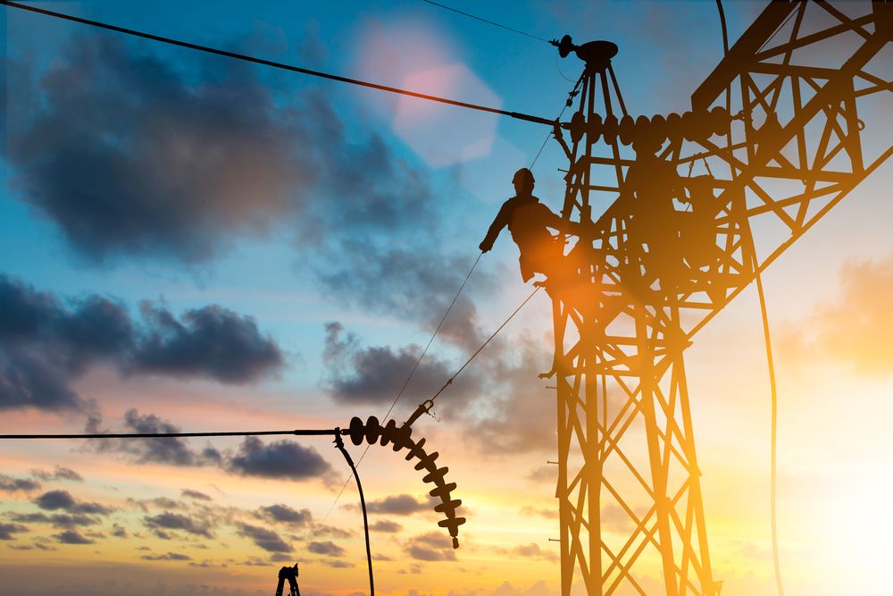A Silhouette Of A Man Working On A Power Line At Sunset — Connect Mid Coast Electrical Services In Taree, NSW
