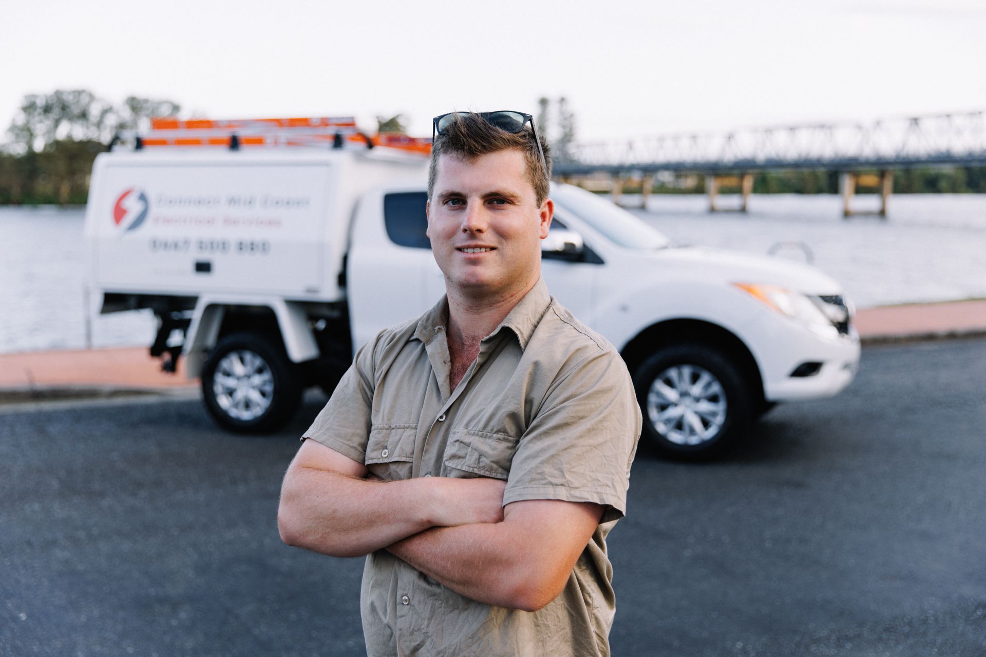 Man standing with arms crossed in front of a white utility truck at a roadside location — Connect Mid Coast Electrical Services In Taree, NSW