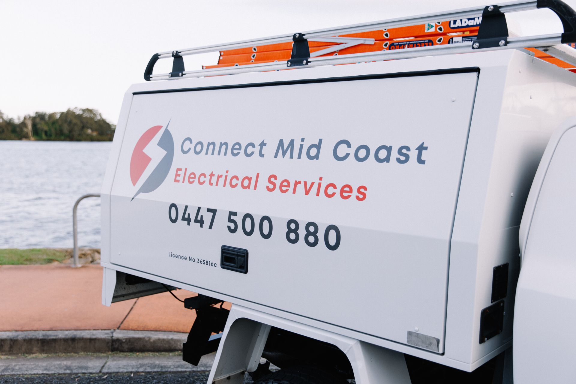 A Man Is Standing In Front Of A Truck With His Arms Crossed — Connect Mid Coast Electrical Services In Taree, NSW