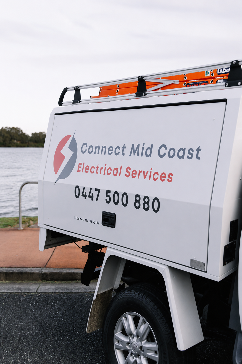 A Man Is Standing In Front Of A Truck With His Arms Crossed — Connect Mid Coast Electrical Services In Taree, NSW