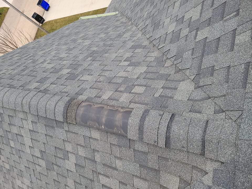 A gray shingled roof with a rectangular ventilation cap installed along the ridge line.