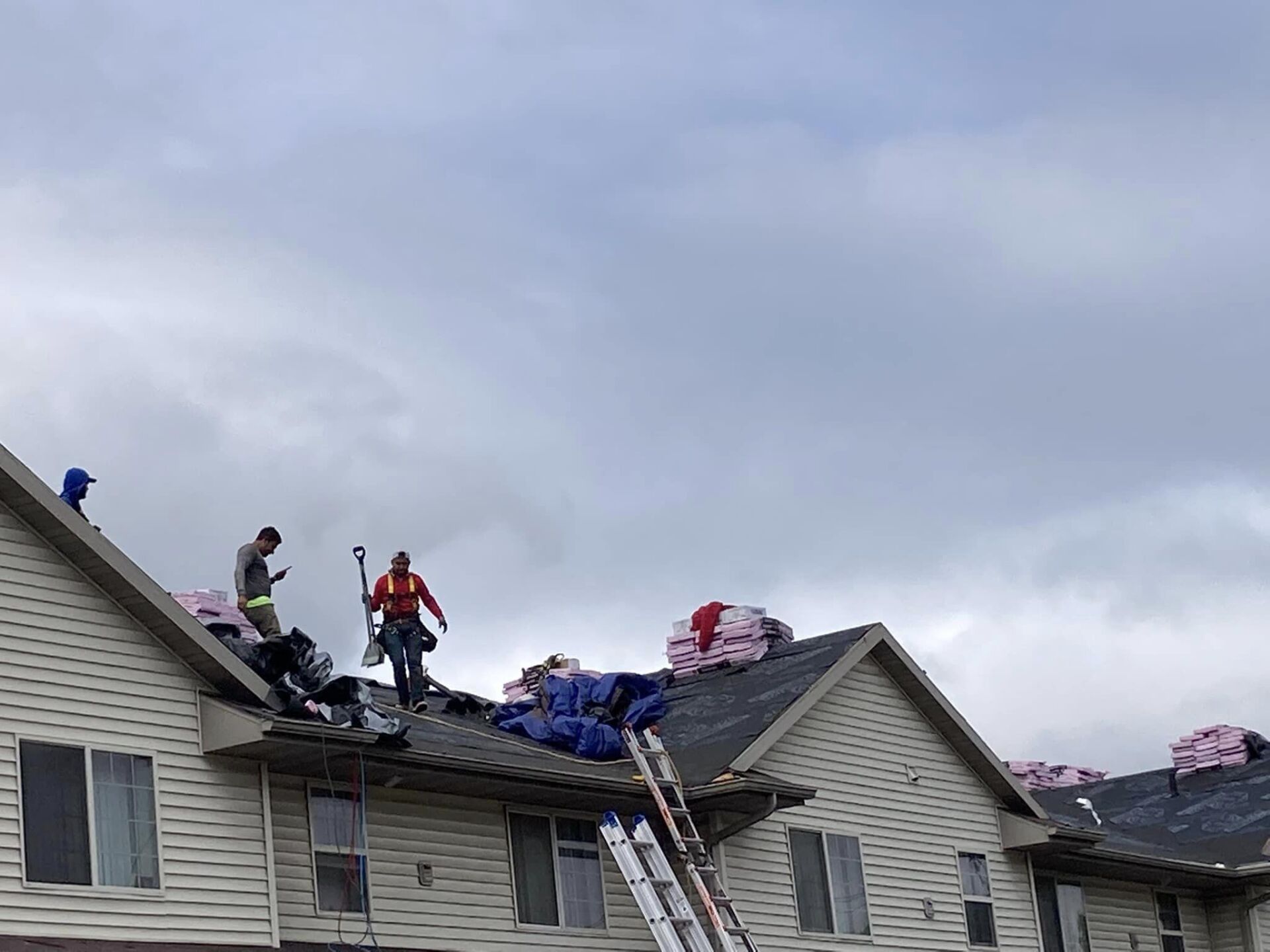 Construction workers remove materials from the roof of a multi-family residential building.
