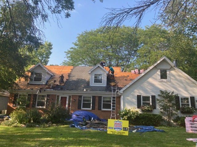 Workers on the roof of a suburban house during a residential roofing project on a sunny day.