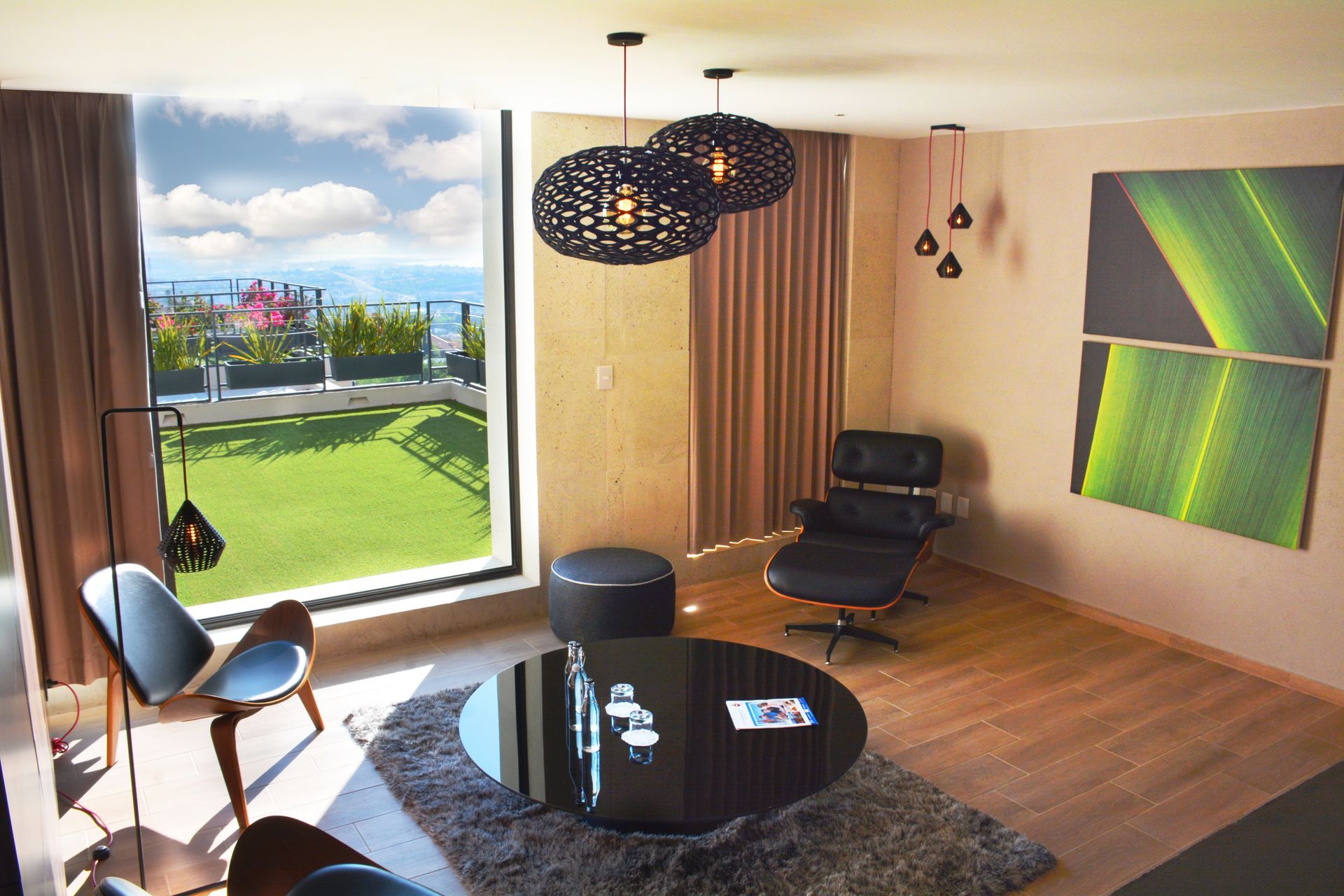 Moderna sala de estar con vista, que cuenta con una mesa de centro redonda negra, un sillón y obras de arte.