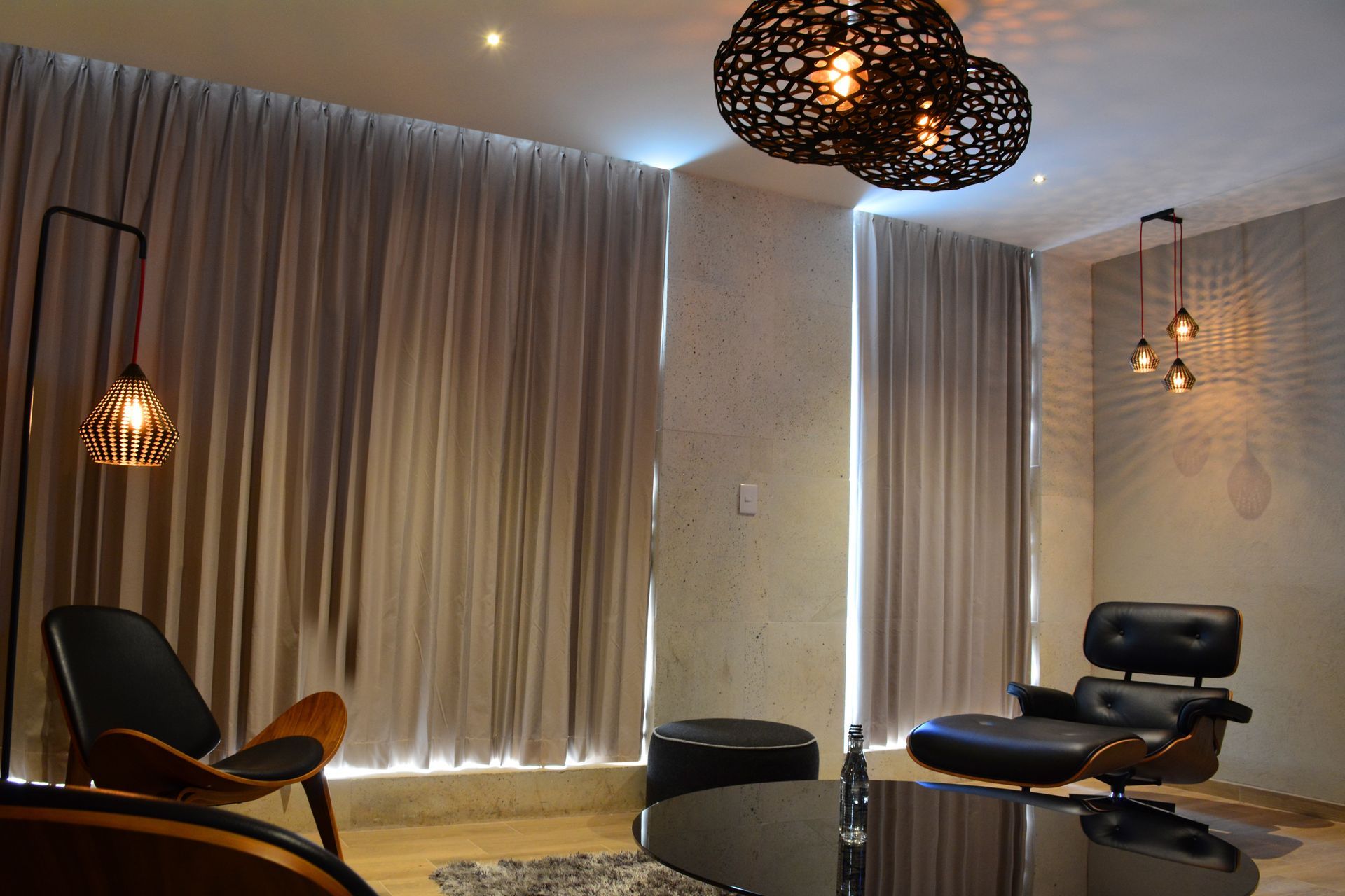 Sala de estar con muebles modernos, cortinas e iluminación decorativa.