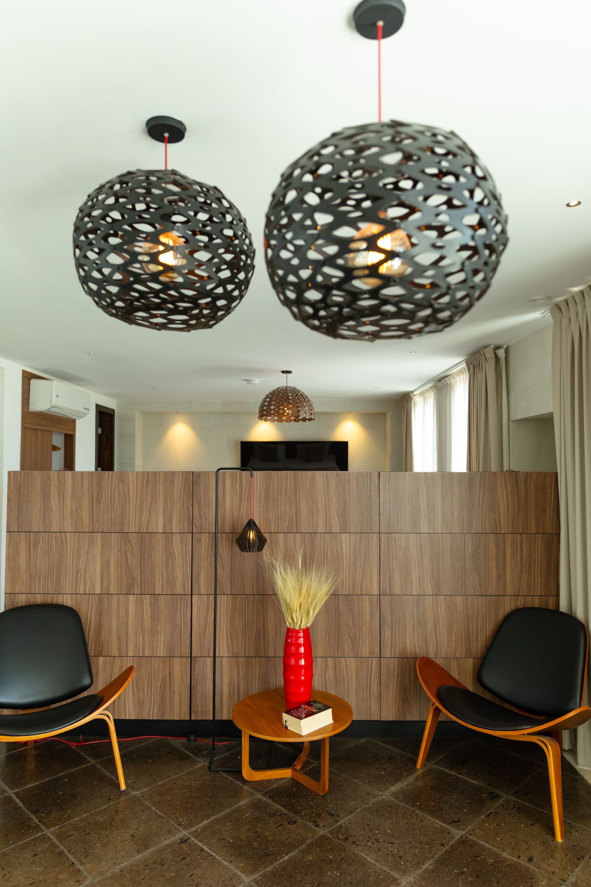 Sala de estar moderna con muebles negros, obras de arte y lámparas estampadas.