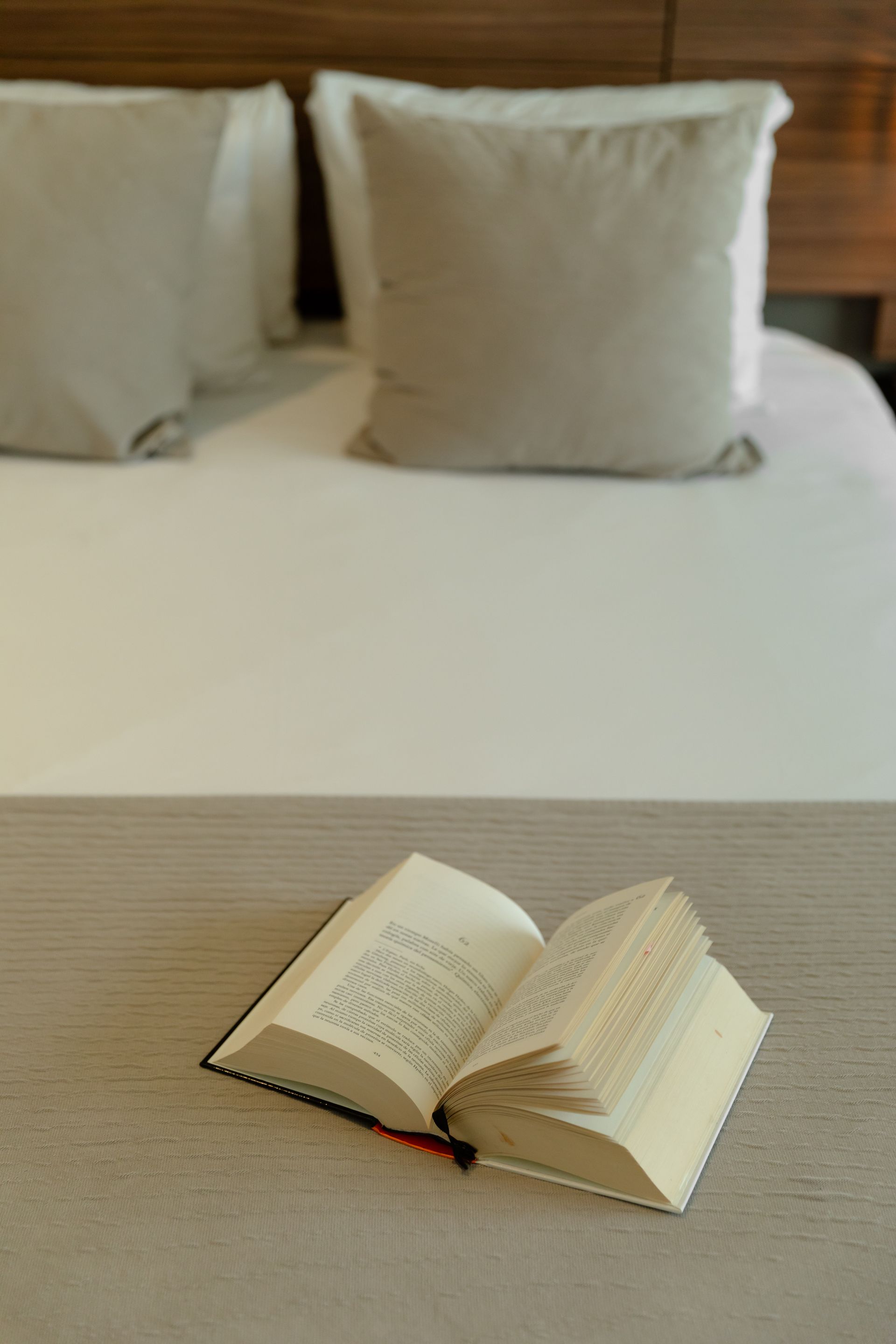 Dormitorio con una cama King, una pared con acento oscuro, dos lámparas colgantes y un sillón gris.