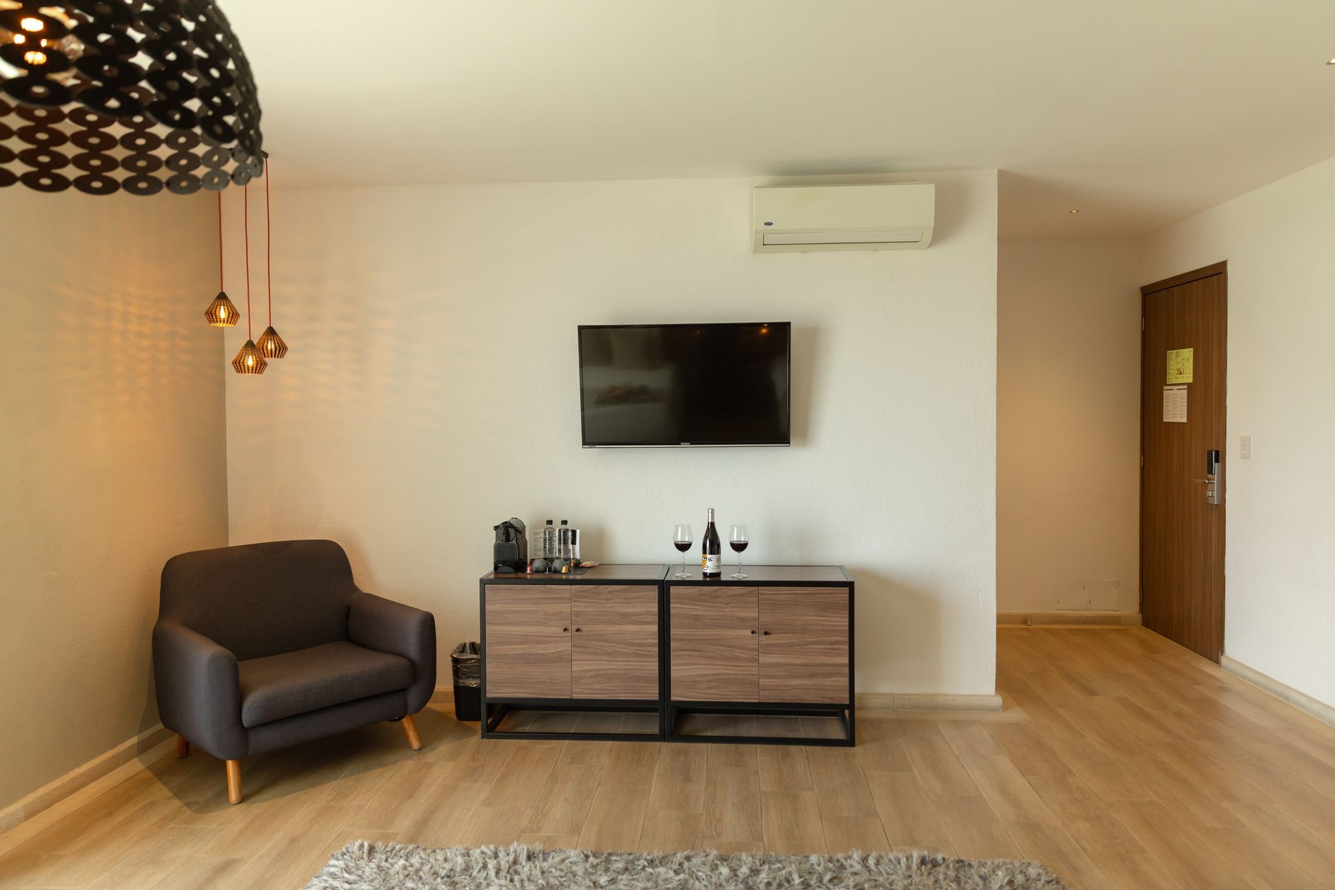 Dormitorio de hotel moderno con cama tamaño king, lámparas decorativas y detalles de madera.