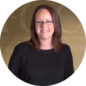 Woman with glasses in a black shirt smiling, in a circular frame with a brown background.