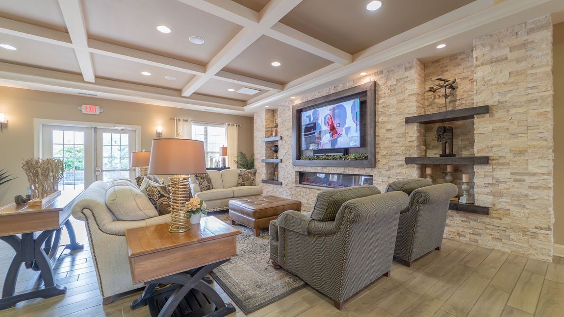 Cozy living room with fireplace, TV, seating, and a beige stone accent wall.