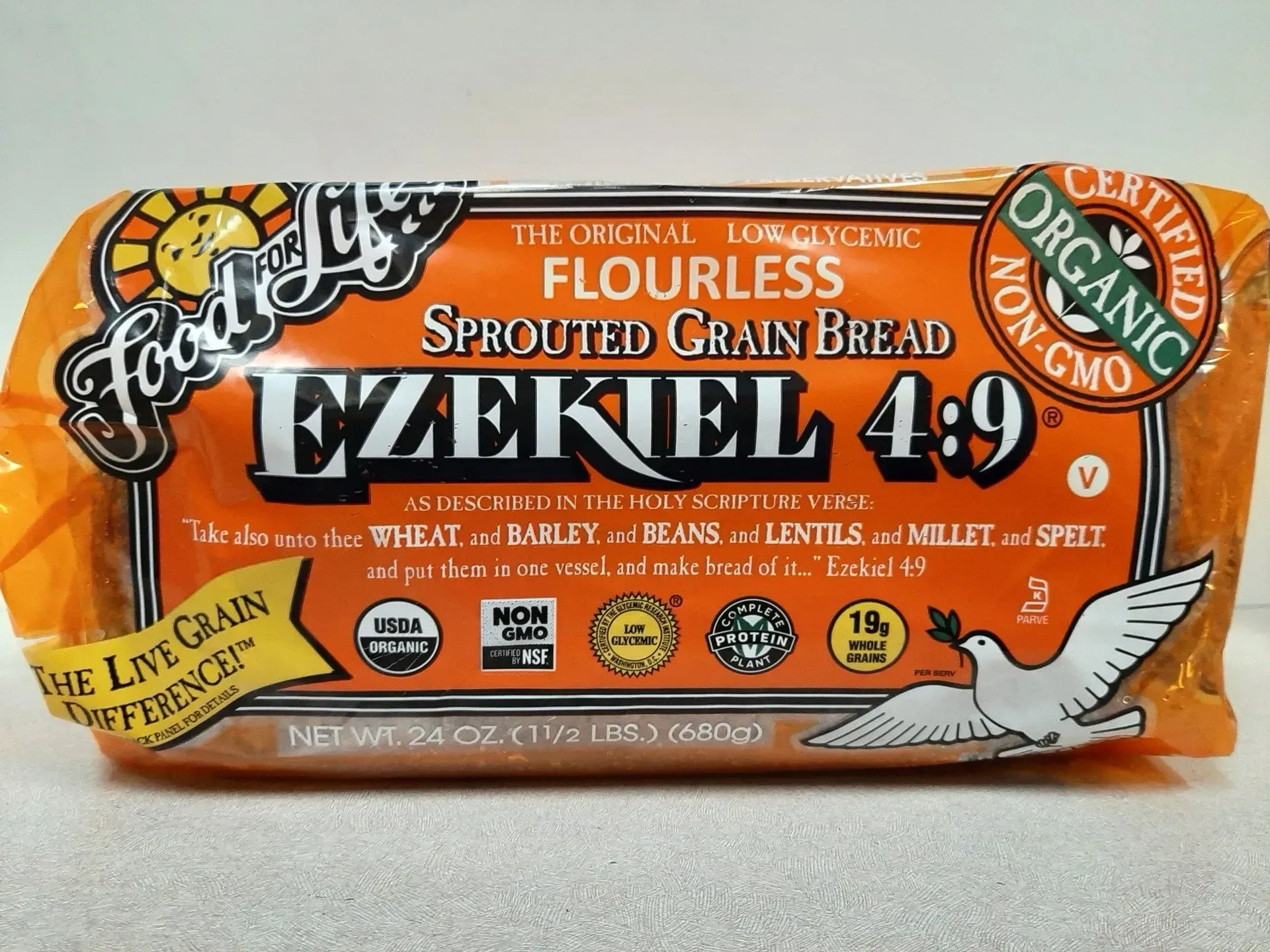 A loaf of Food for Life Ezekiel 4:9 flourless sprouted grain bread in its orange plastic packaging.