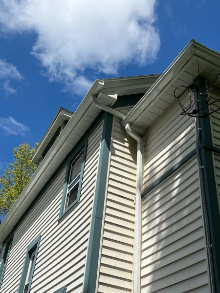 Seen from below, a gutter system successfully installed on yellow and green house