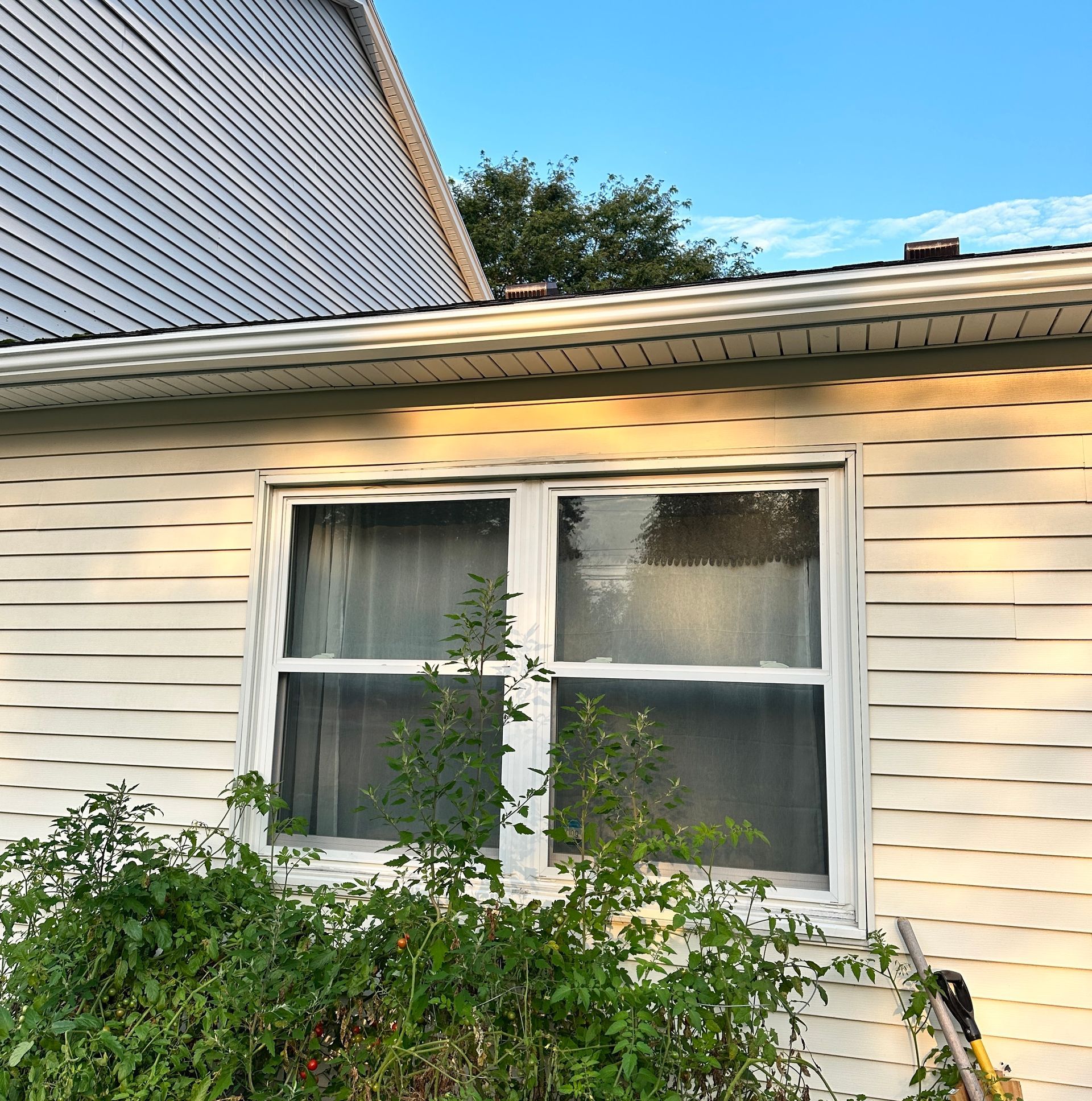 New gutters installed on a yellow house, seen above a double window from the side